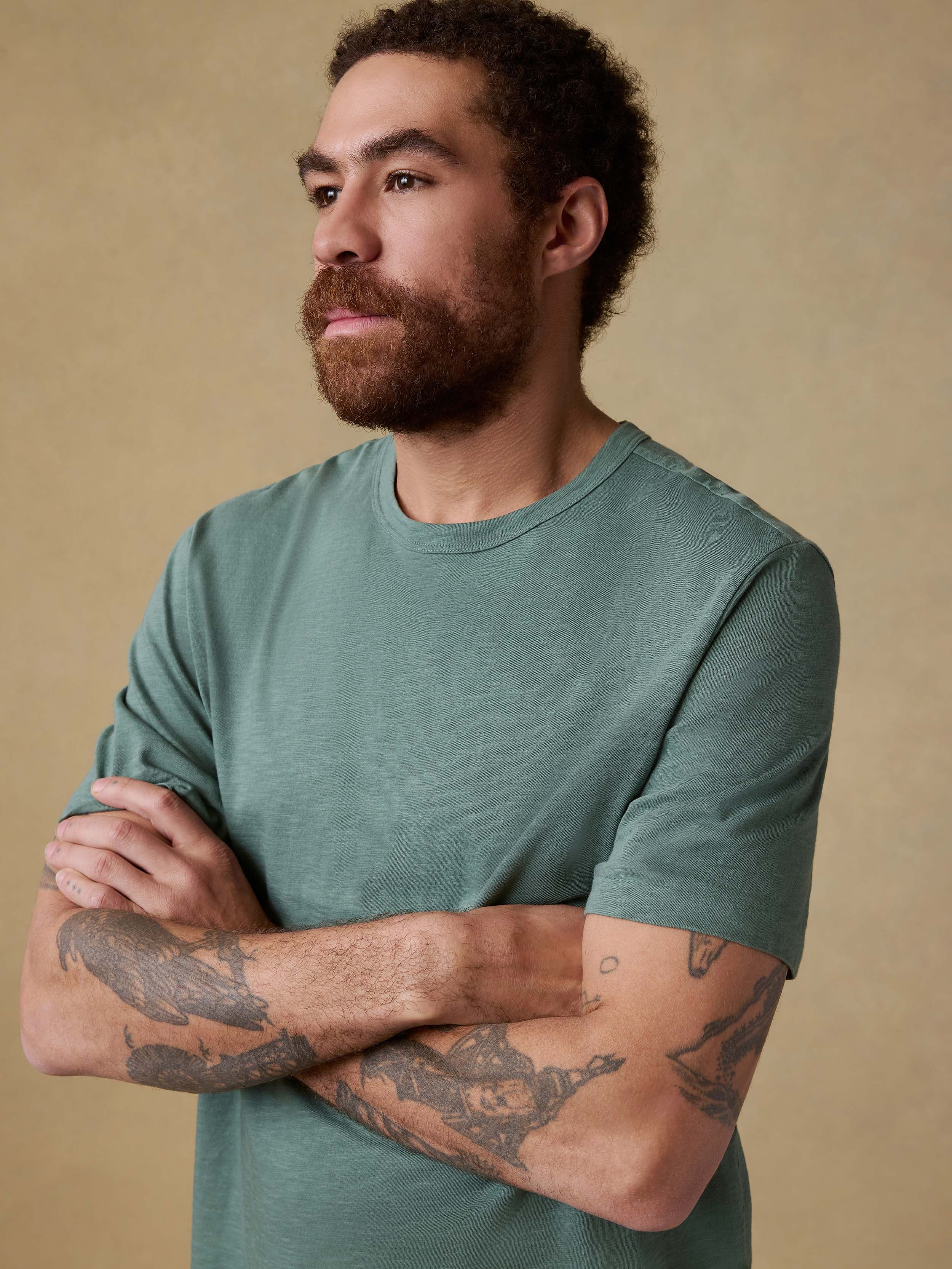 Man wearing a green t-shirt against a beige background