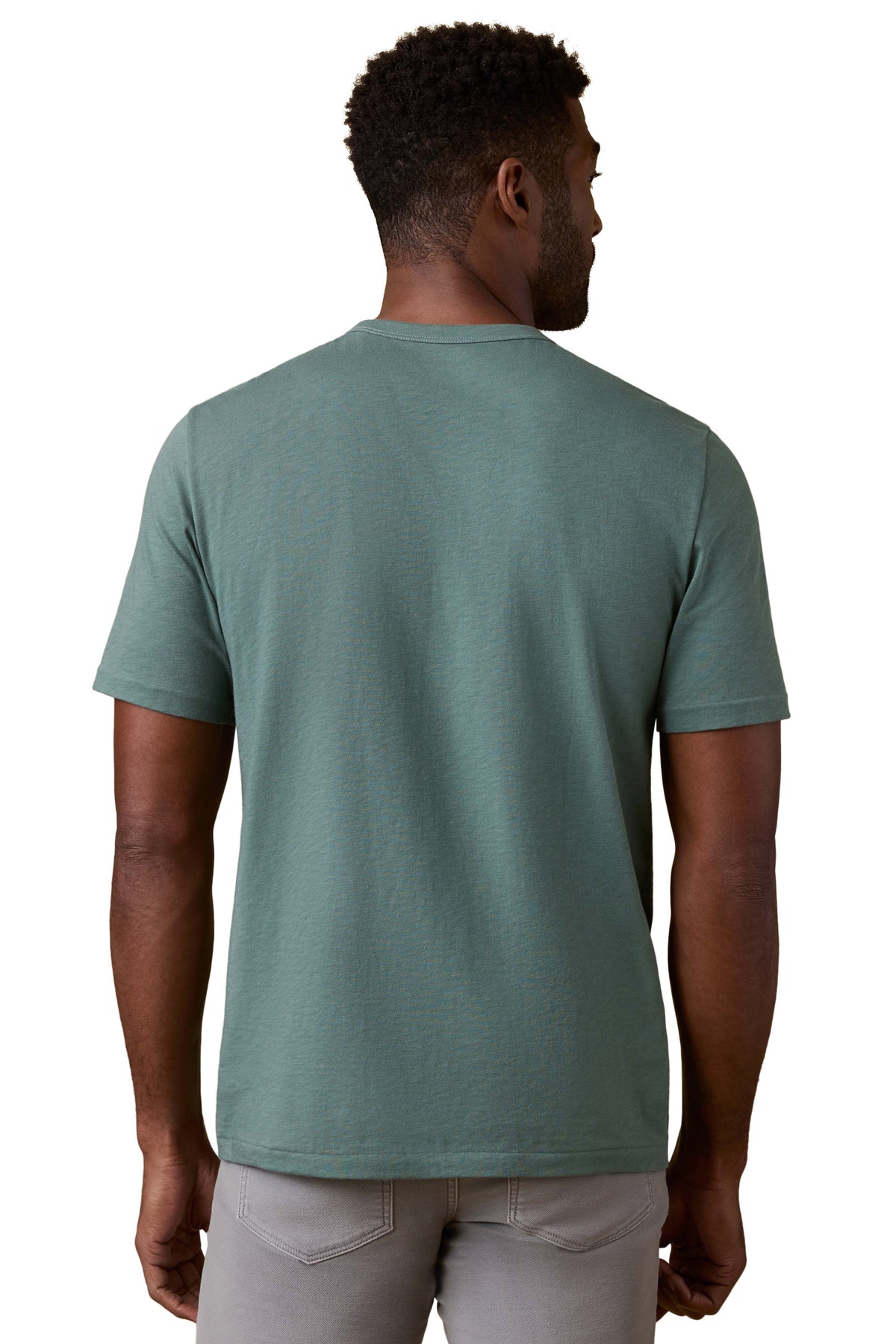 A man viewed from behind wearing a green tee and grey pants, image 3 of 3