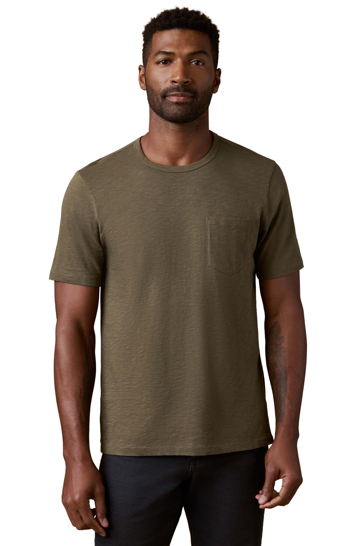 A man wearing a green tee and black jeans, image 1 of 3