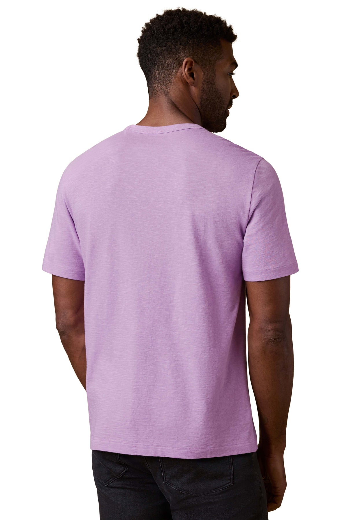 A man viewed from behind wearing a purple tee and black jeans, image 3 of 3