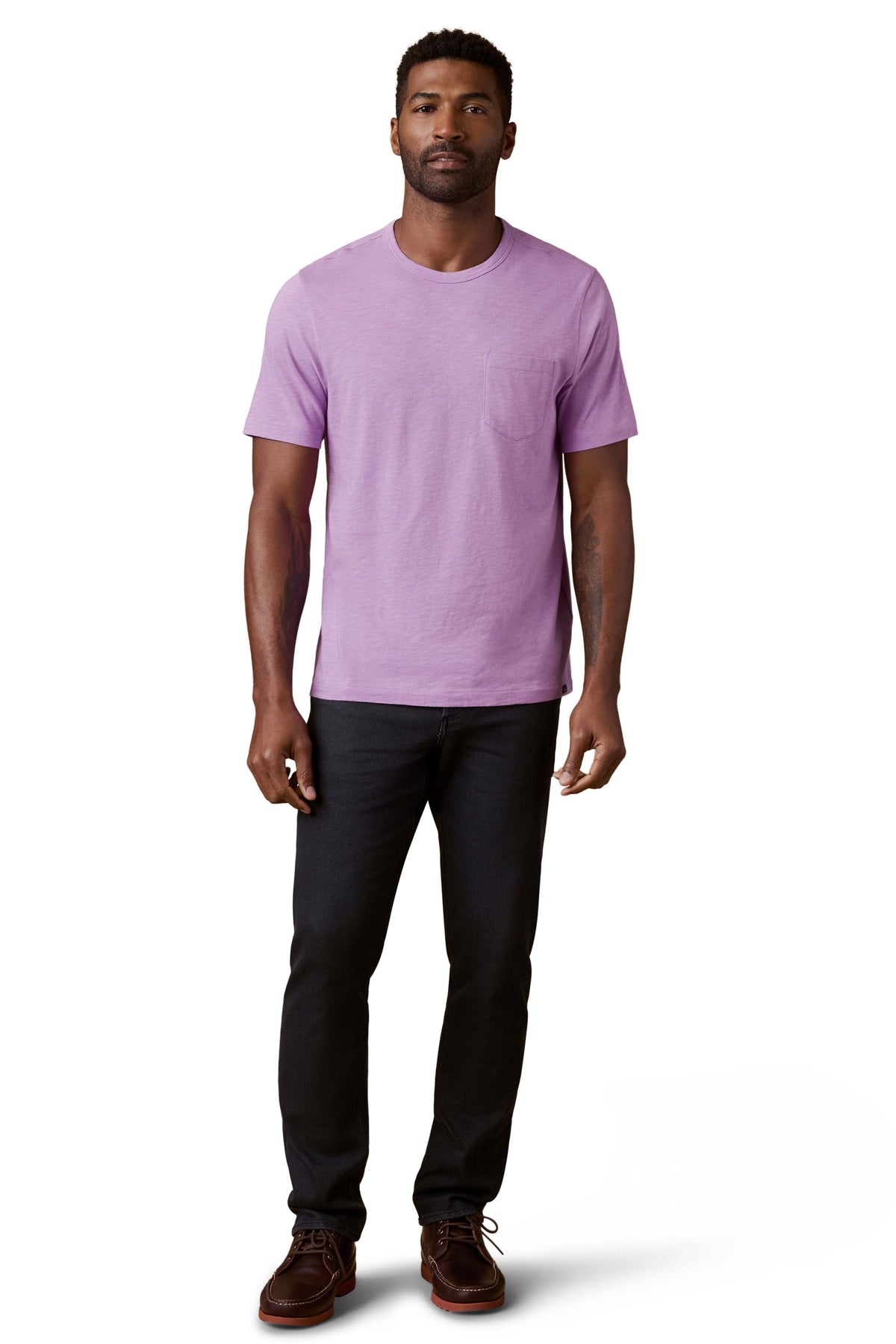 A man wearing a purple tee, black jeans, and brown shoes, image 2 of 3