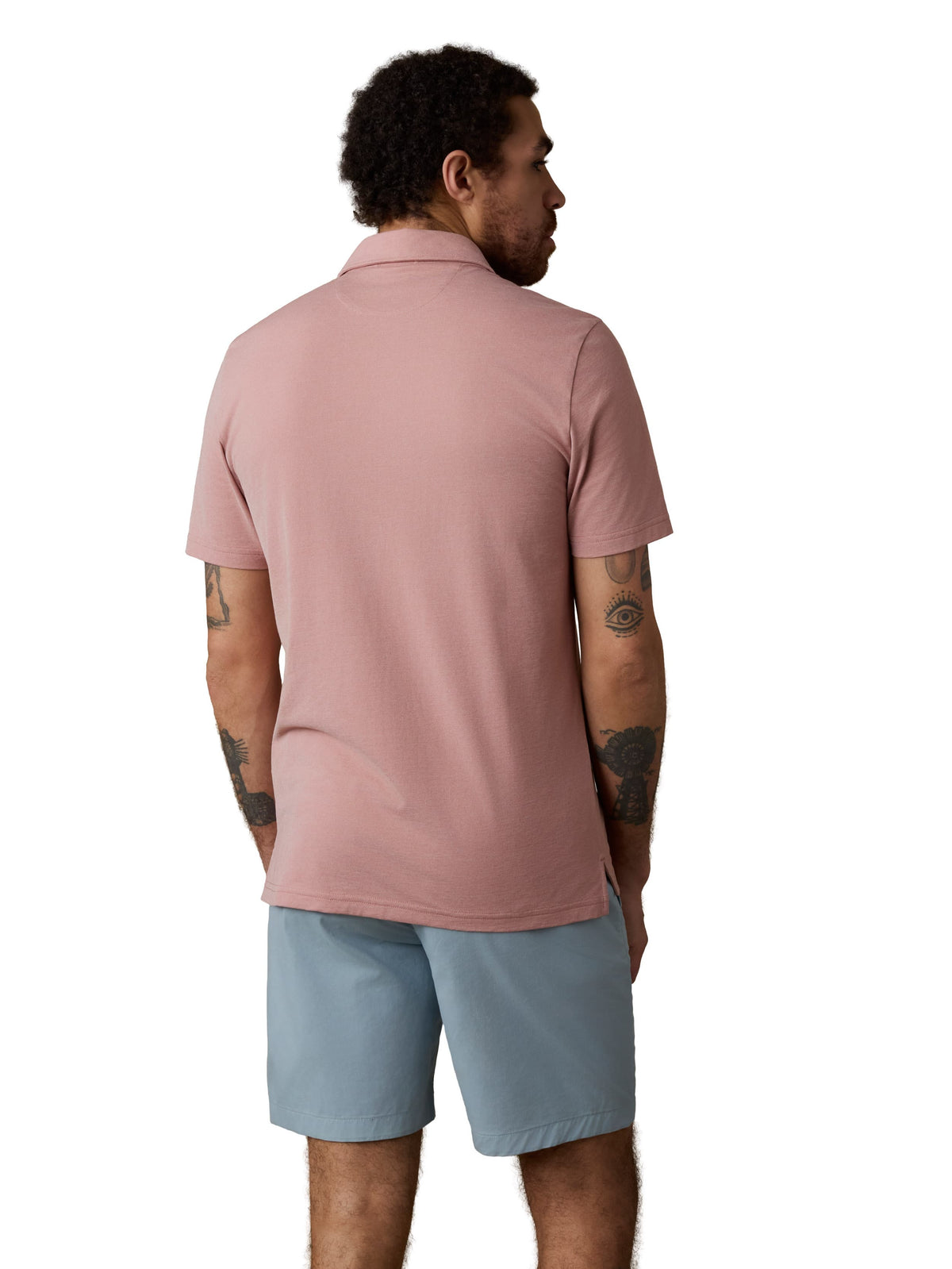 A man viewed from behind wearing a pink polo and light blue shorts, image 3 of 3
