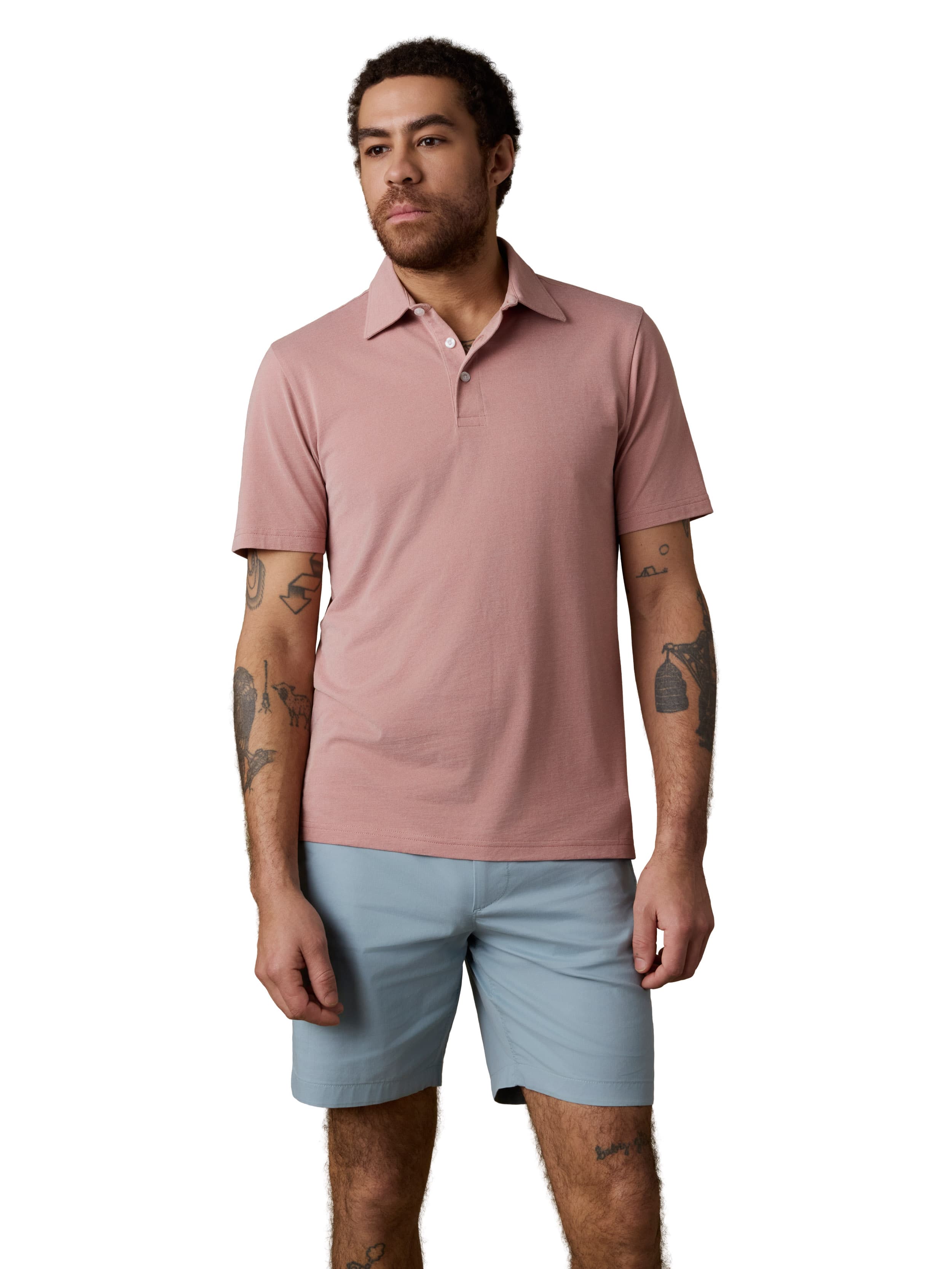 A man wearing a pink polo and light blue shorts