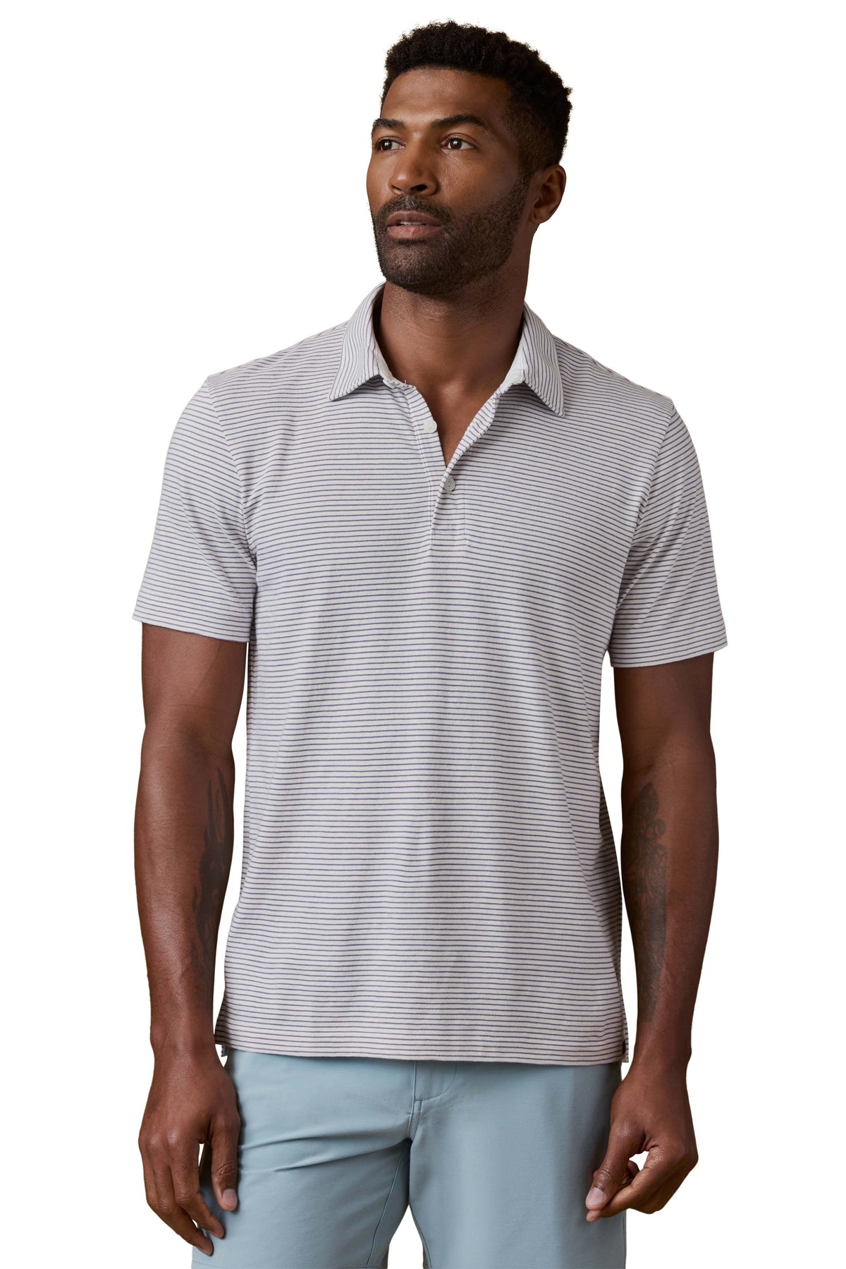 A man wearing a striped polo shirt and blue shorts, image 1 of 3
