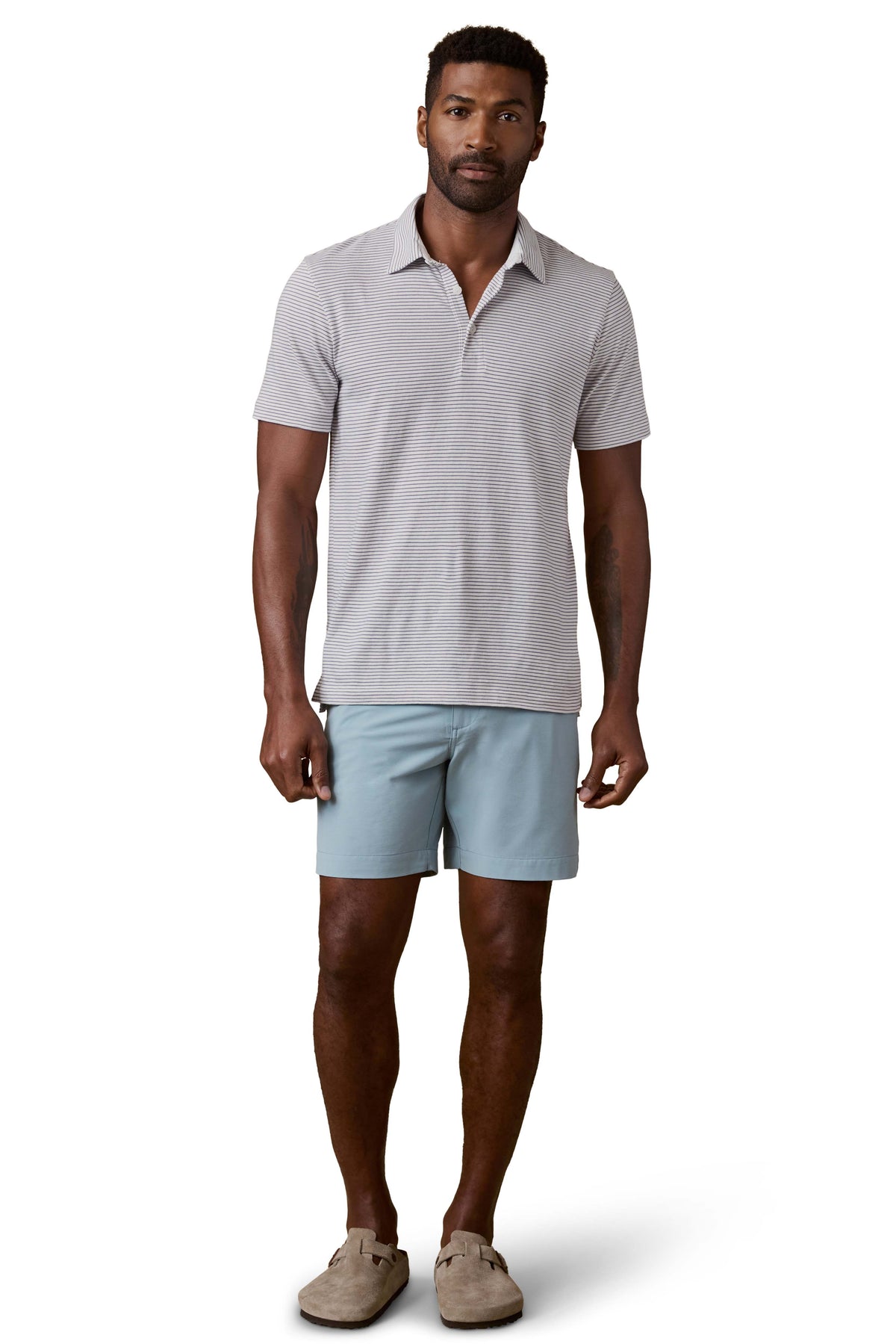 A man wearing a striped polo shirt, blue shorts, and birkenstocks, image 2 of 3