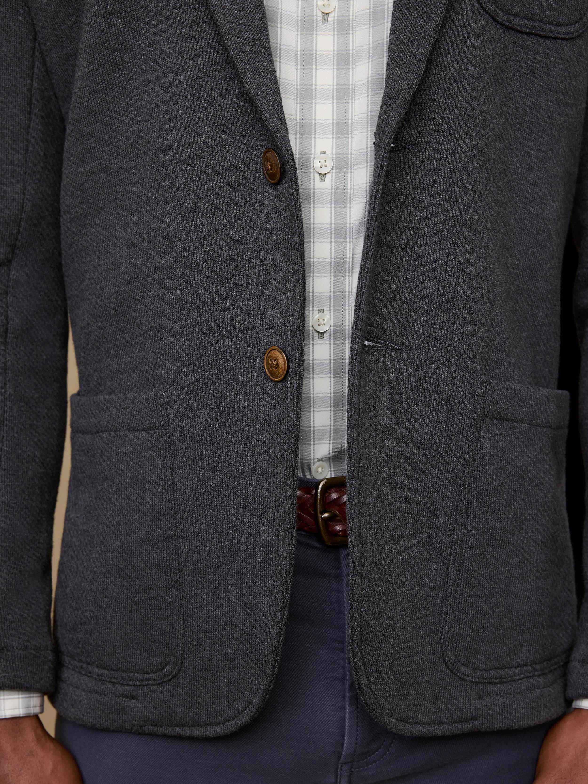 Detail shot of a man wearing a gray blazer with brown buttons worn over a checkered shirt.