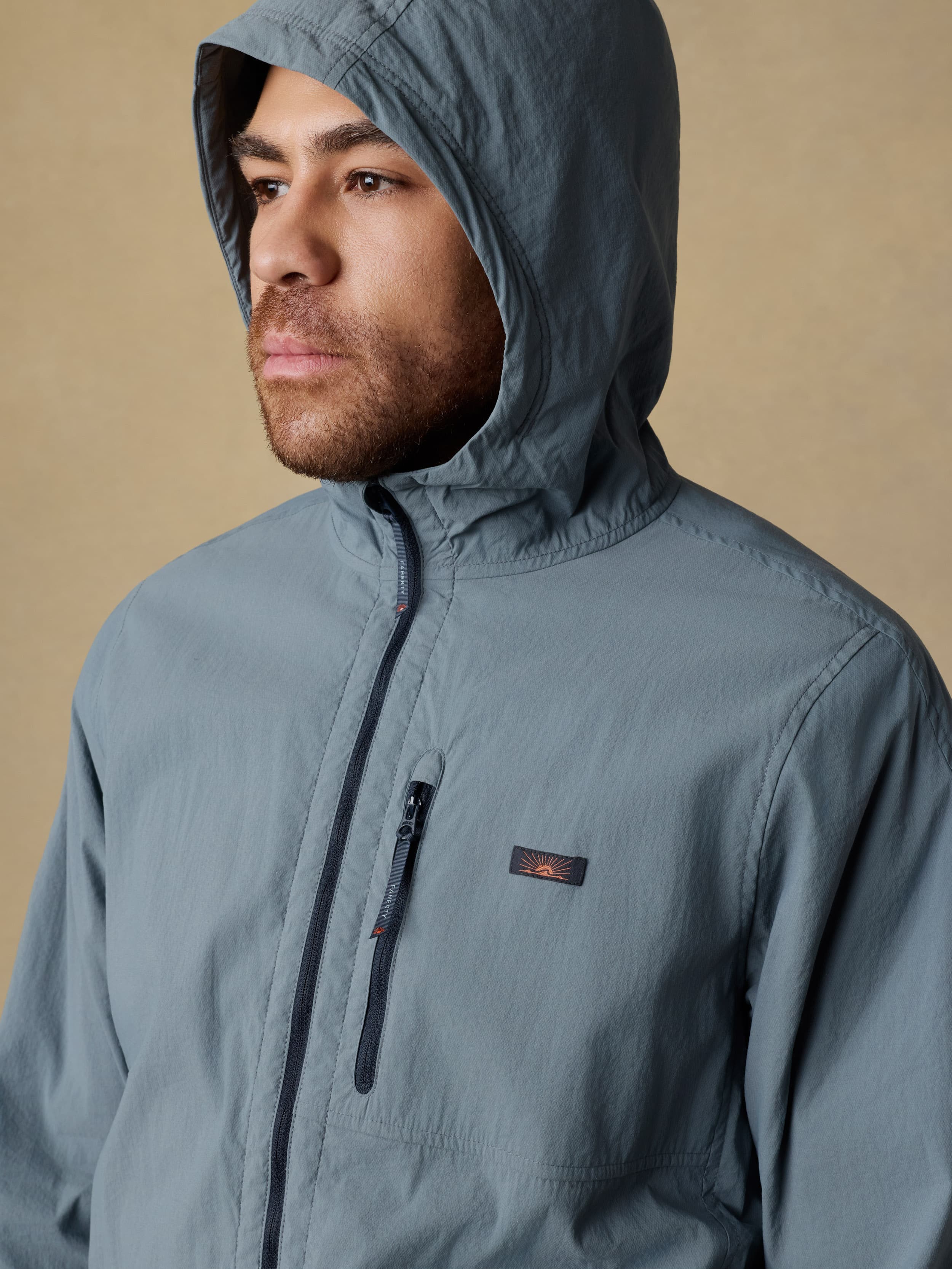 Man wearing a blue jacket against a beige background