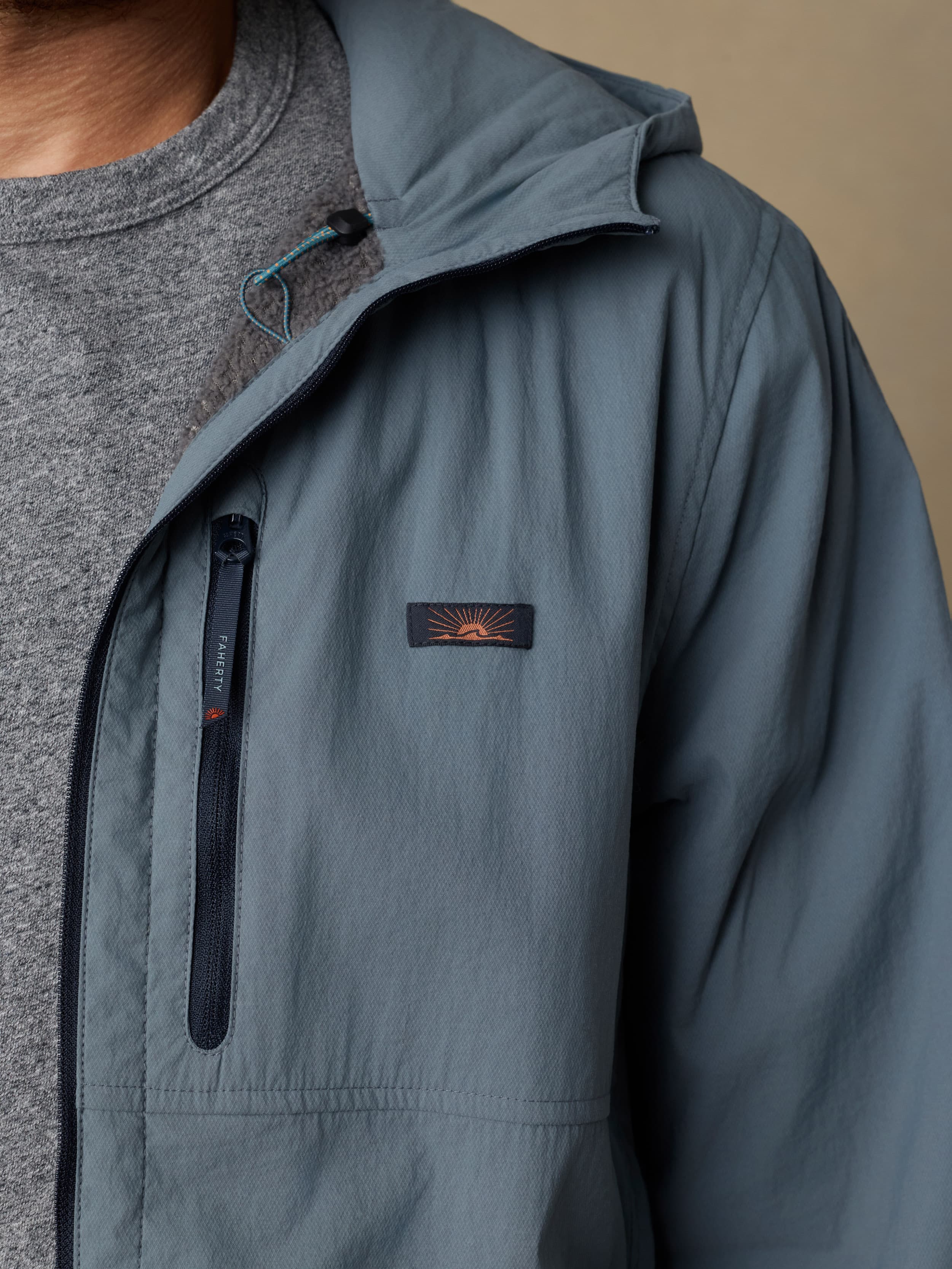 Man wearing a blue jacket with a visible Faherty brand logo at the left chest against a beige background