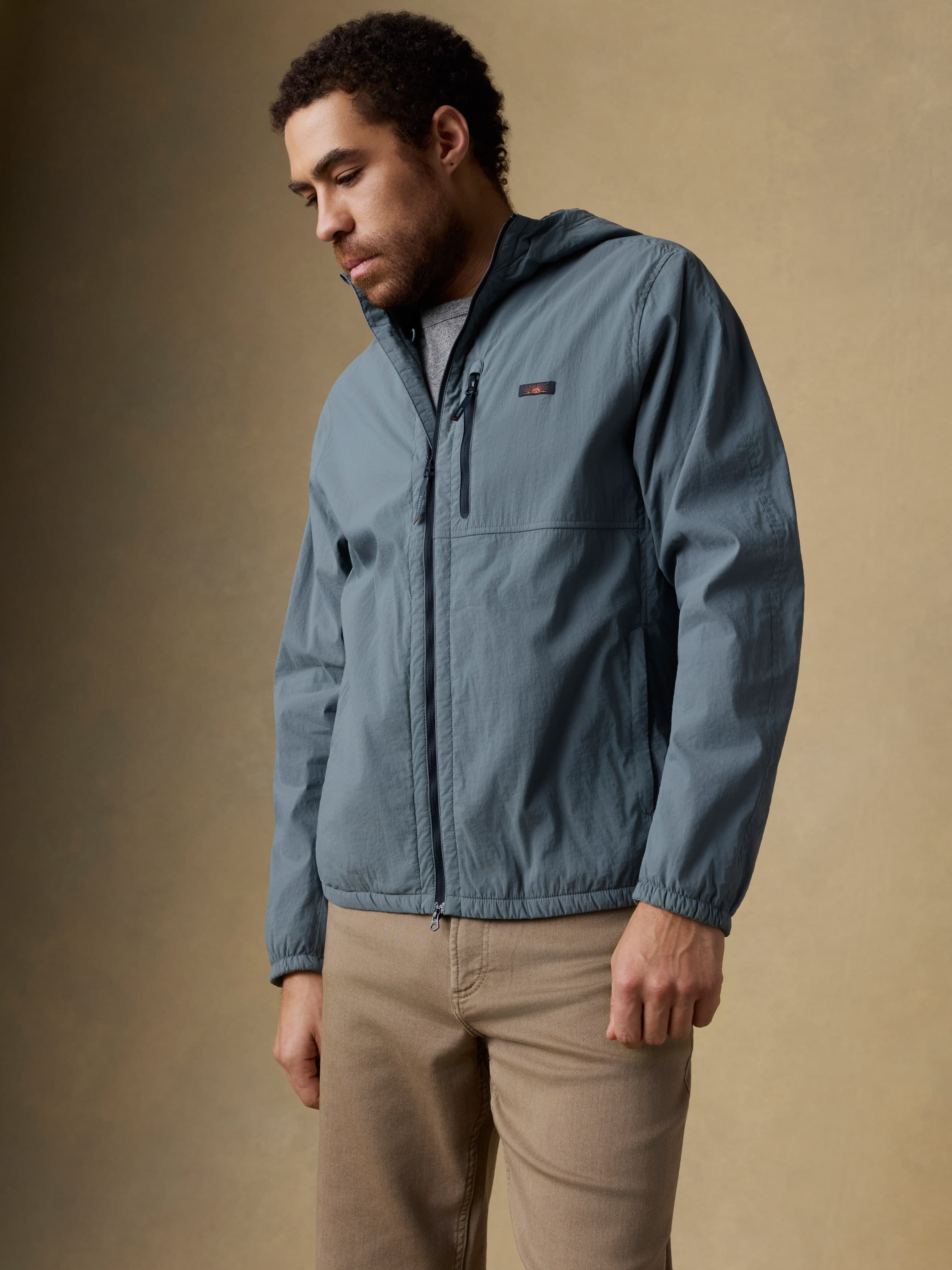 Man wearing a blue jacket and beige pants against a beige background