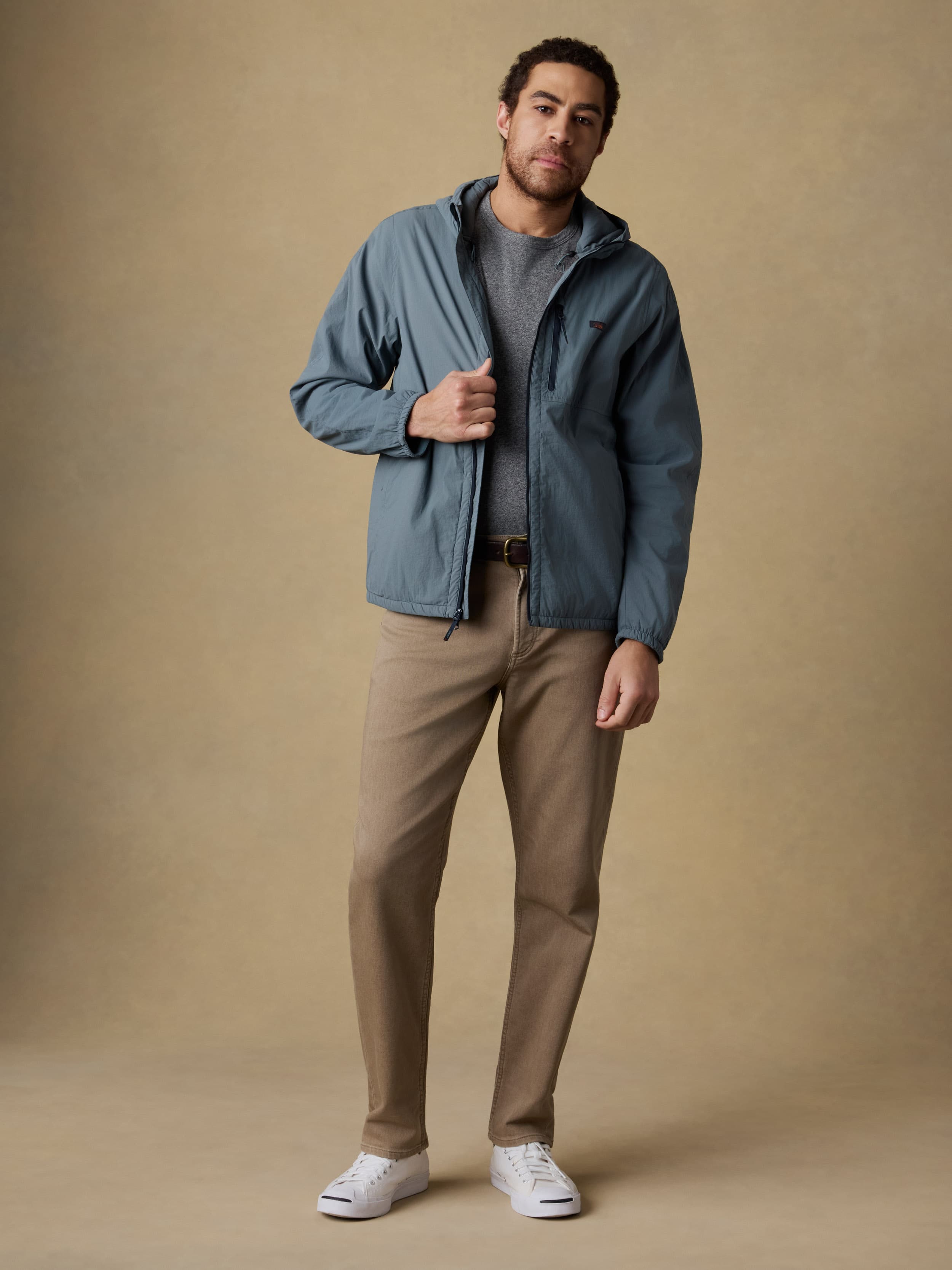 Man wearing a blue jacket and beige pants against a beige background