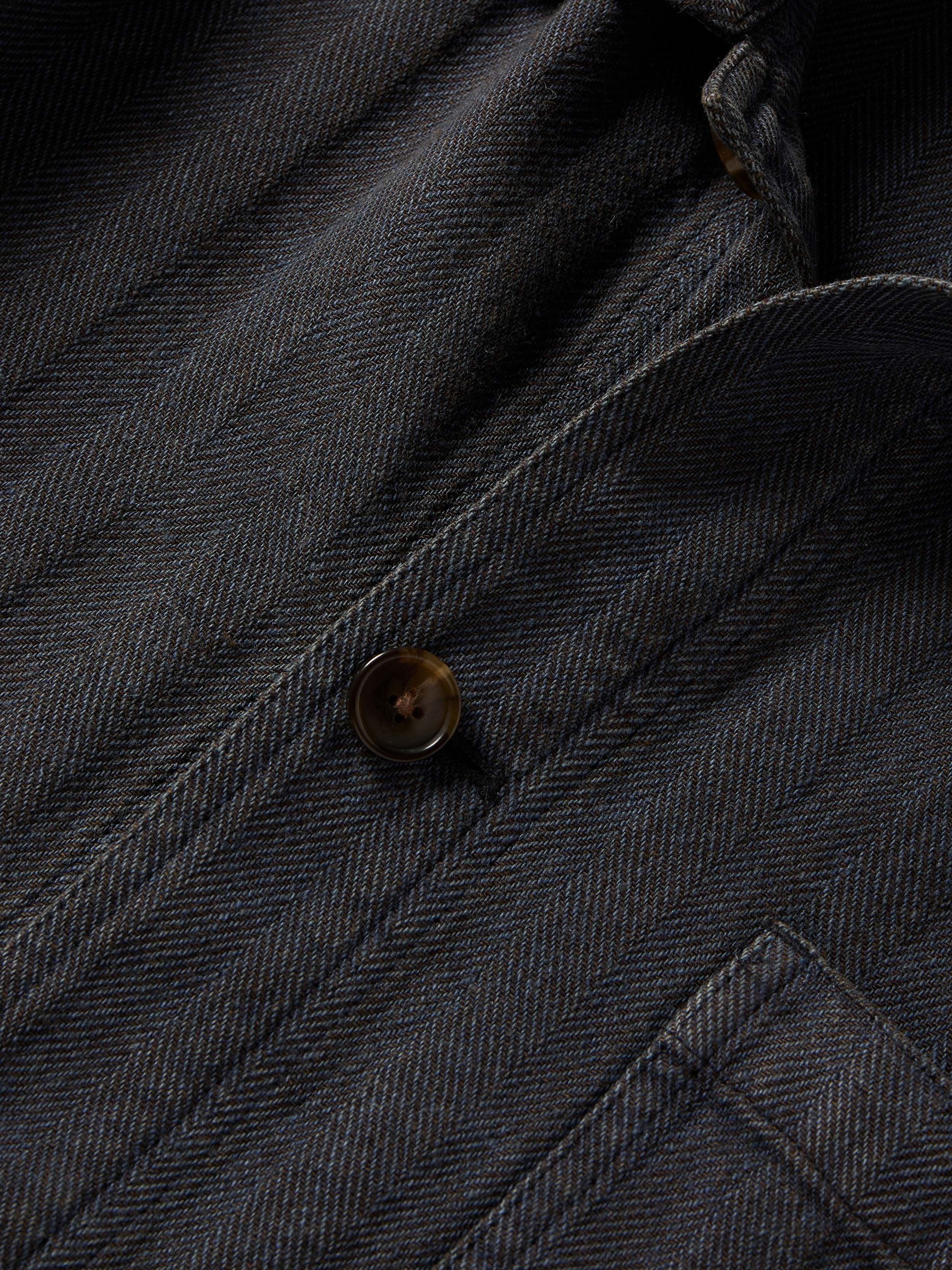 Close-up of a dark grey herringbone jacket with button detail