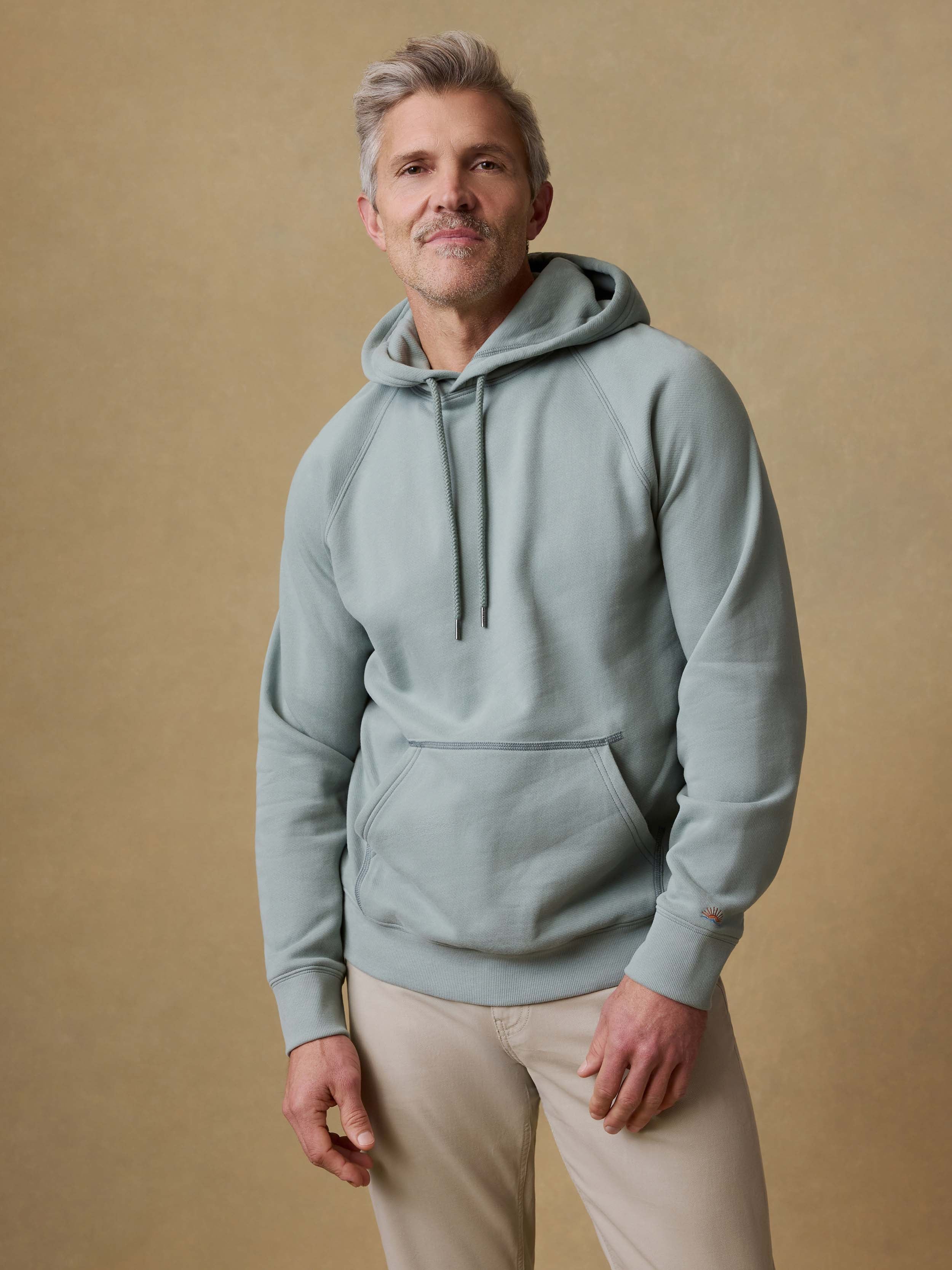 Man wearing a light green hoodie against a beige background