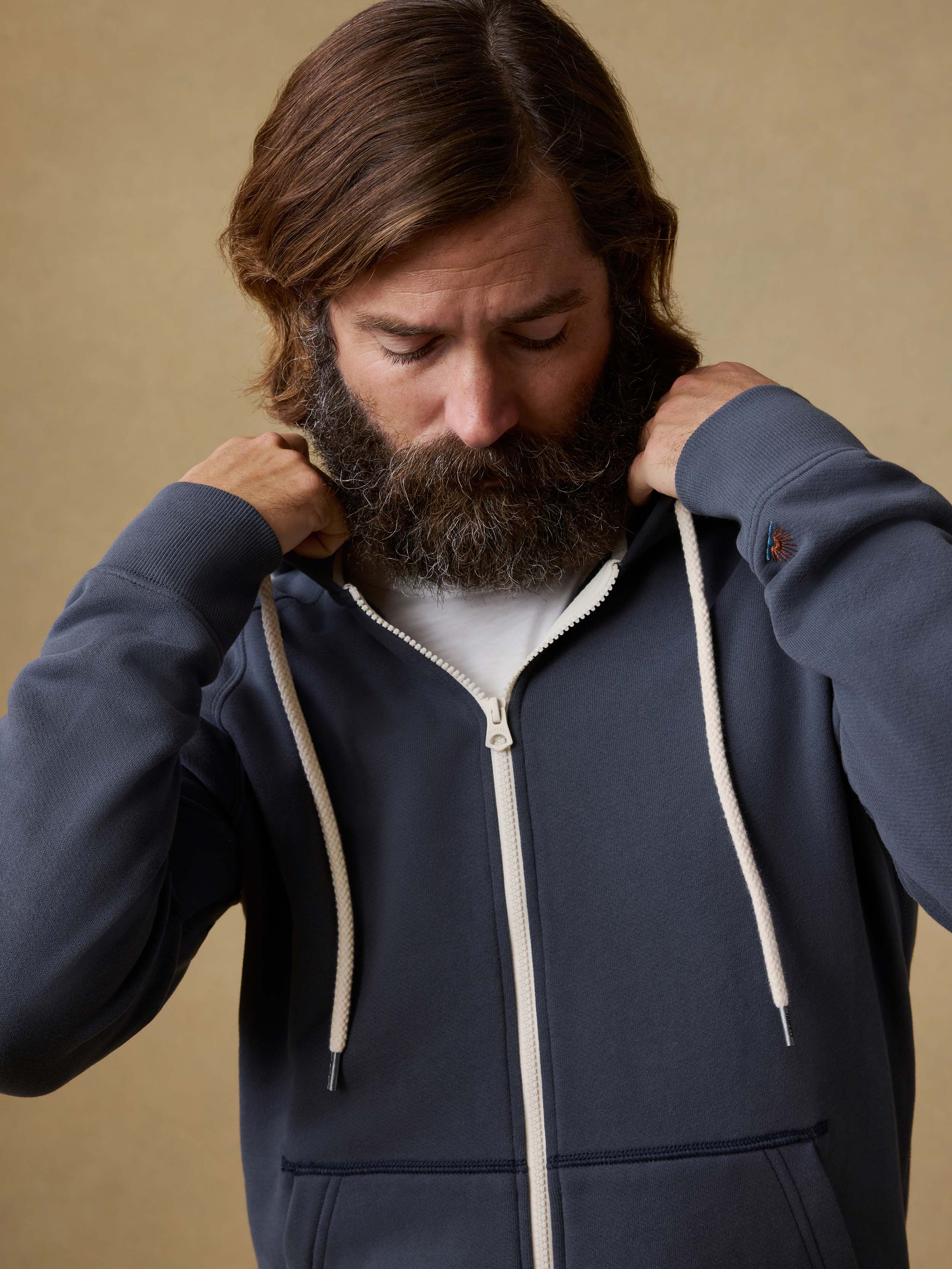 Man wearing a navy blue hoodie with a beige background