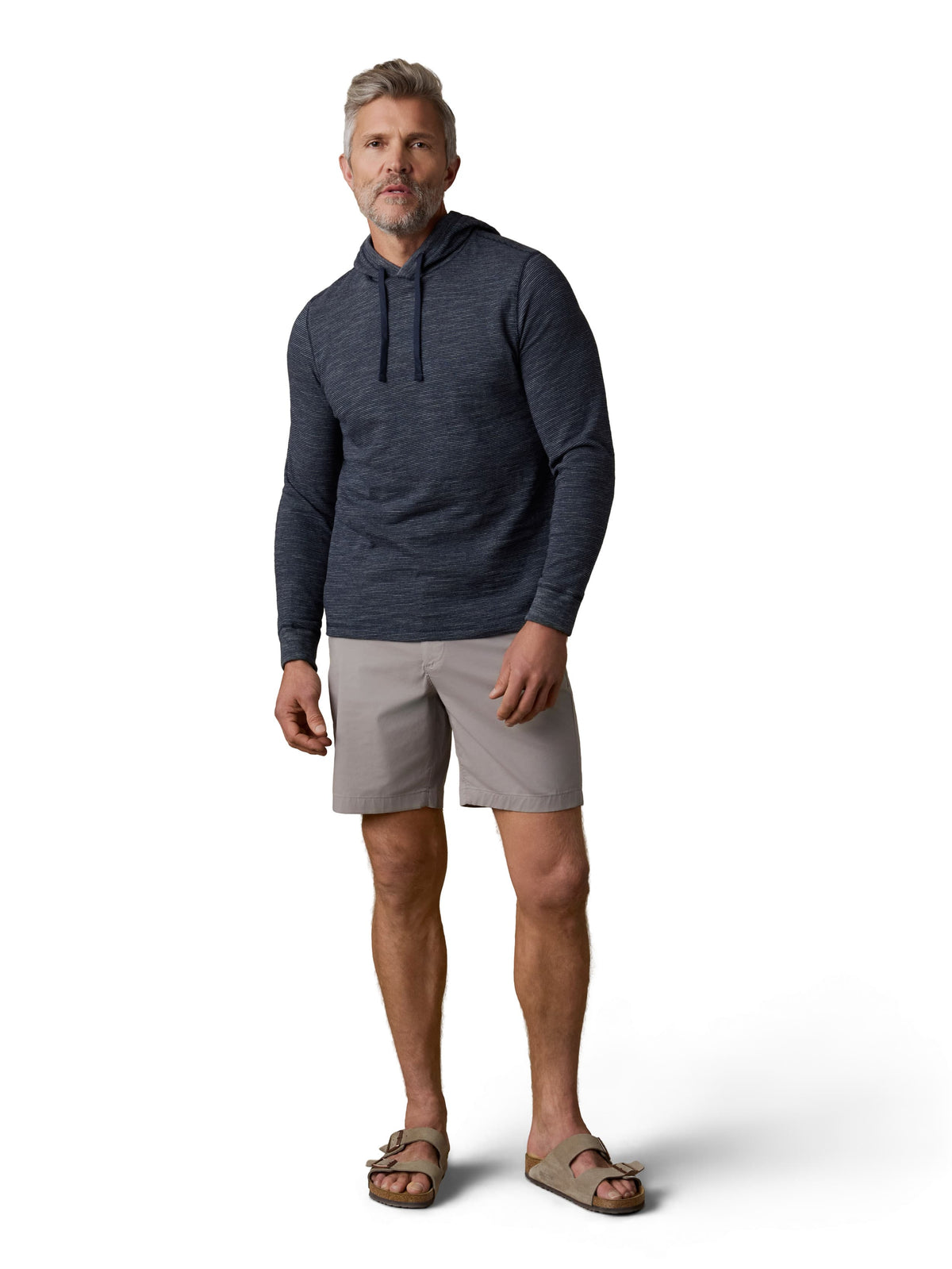 A man wearing a navy hoodie, grey shorts, and birkenstocks, image 2 of 3