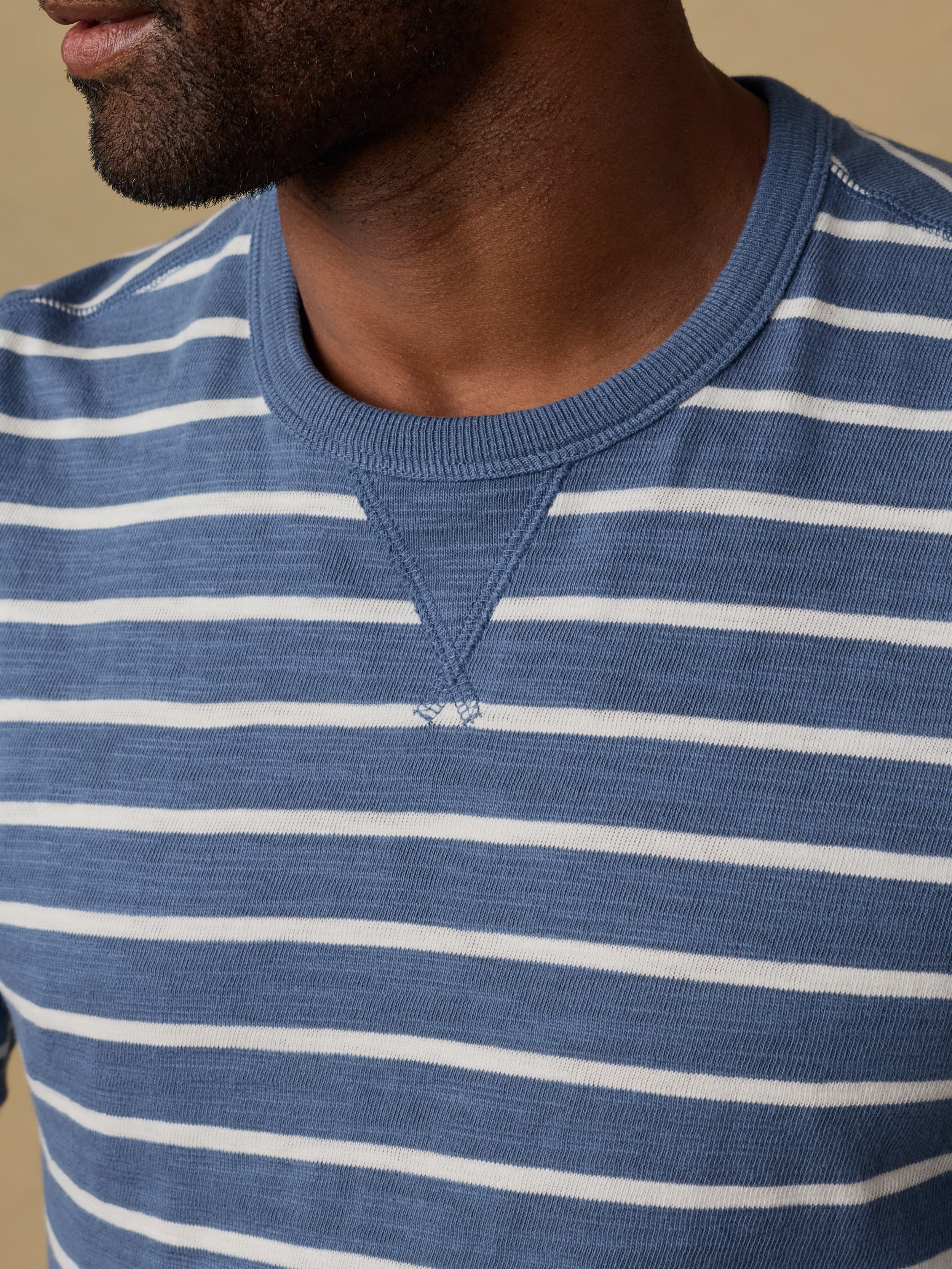 Close-up of a man wearing a blue and white striped crewneck sweatshirt.