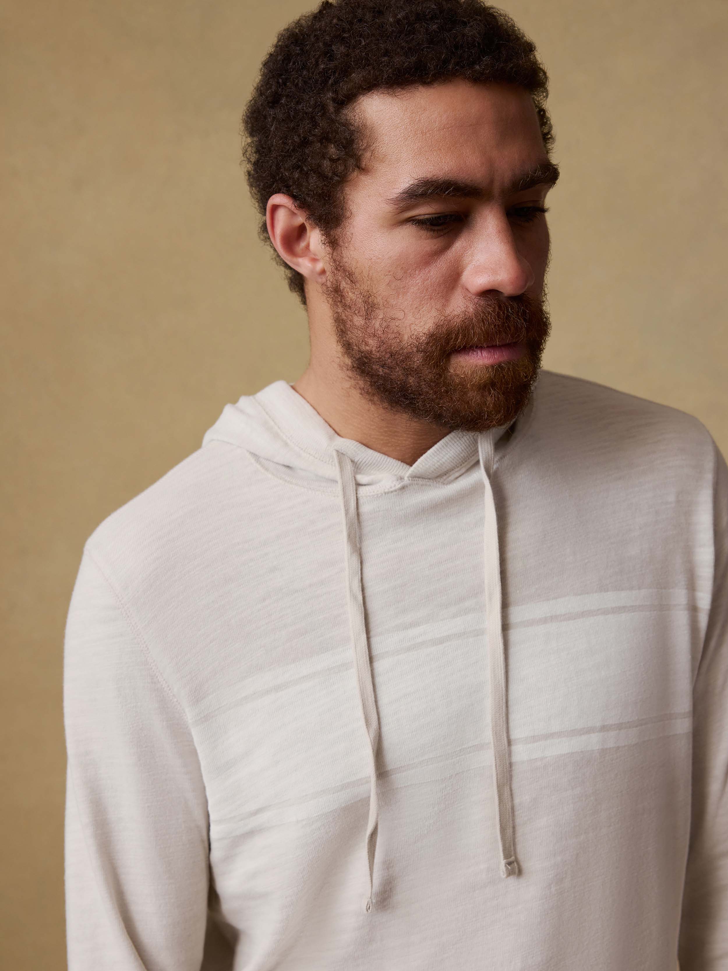 Man wearing a beige hoodie against a beige background