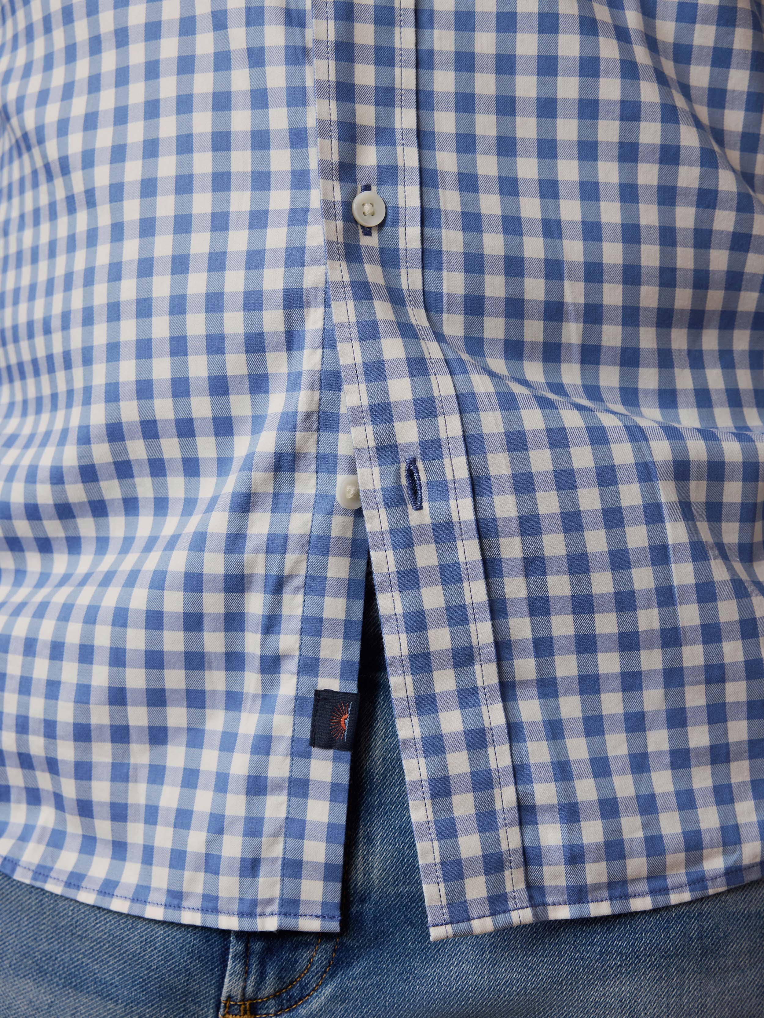 Close-up of a blue and white checkered shirt with a Faherty brand logo at the hem