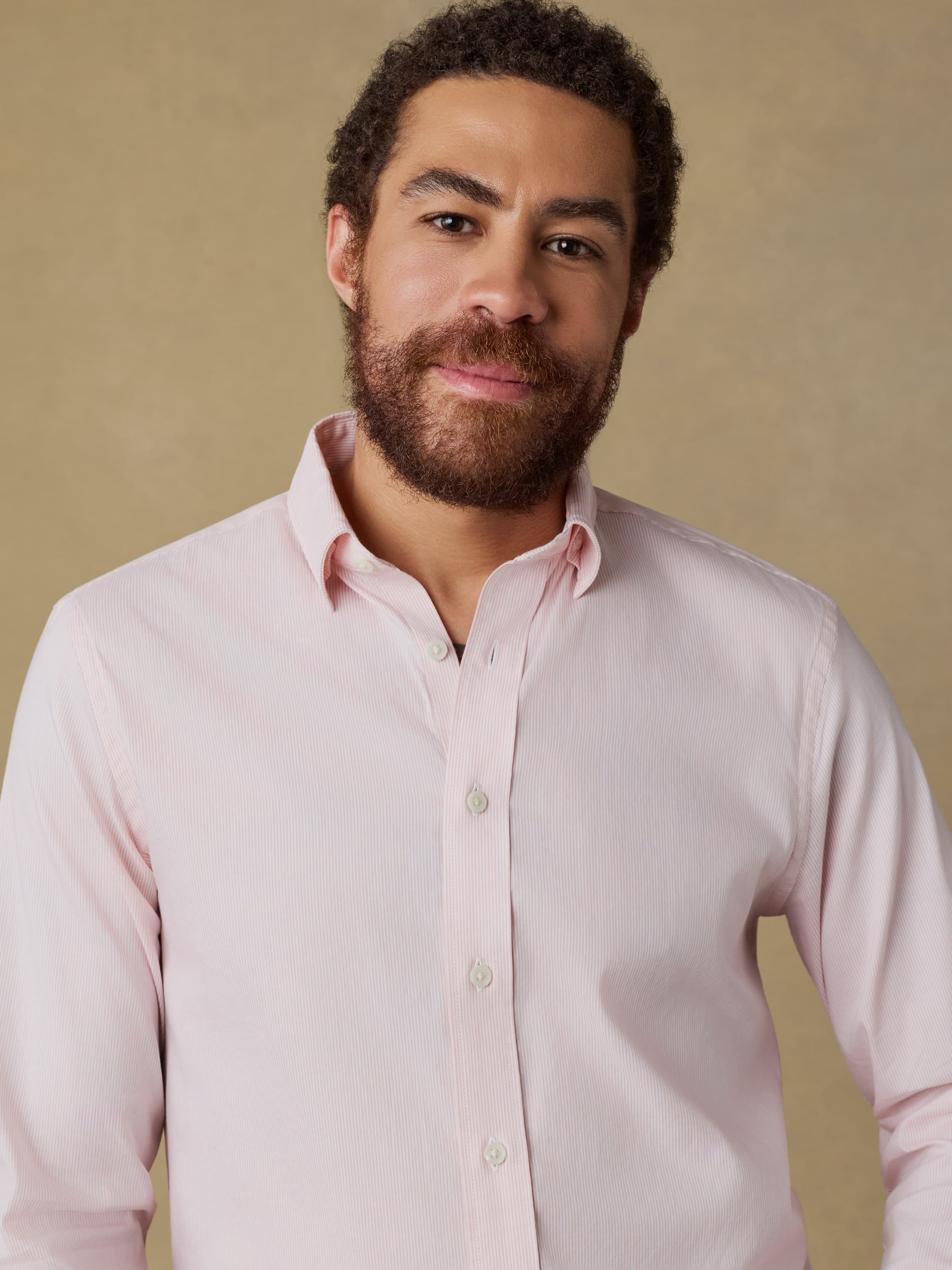 Man wearing a light pink shirt against a beige background