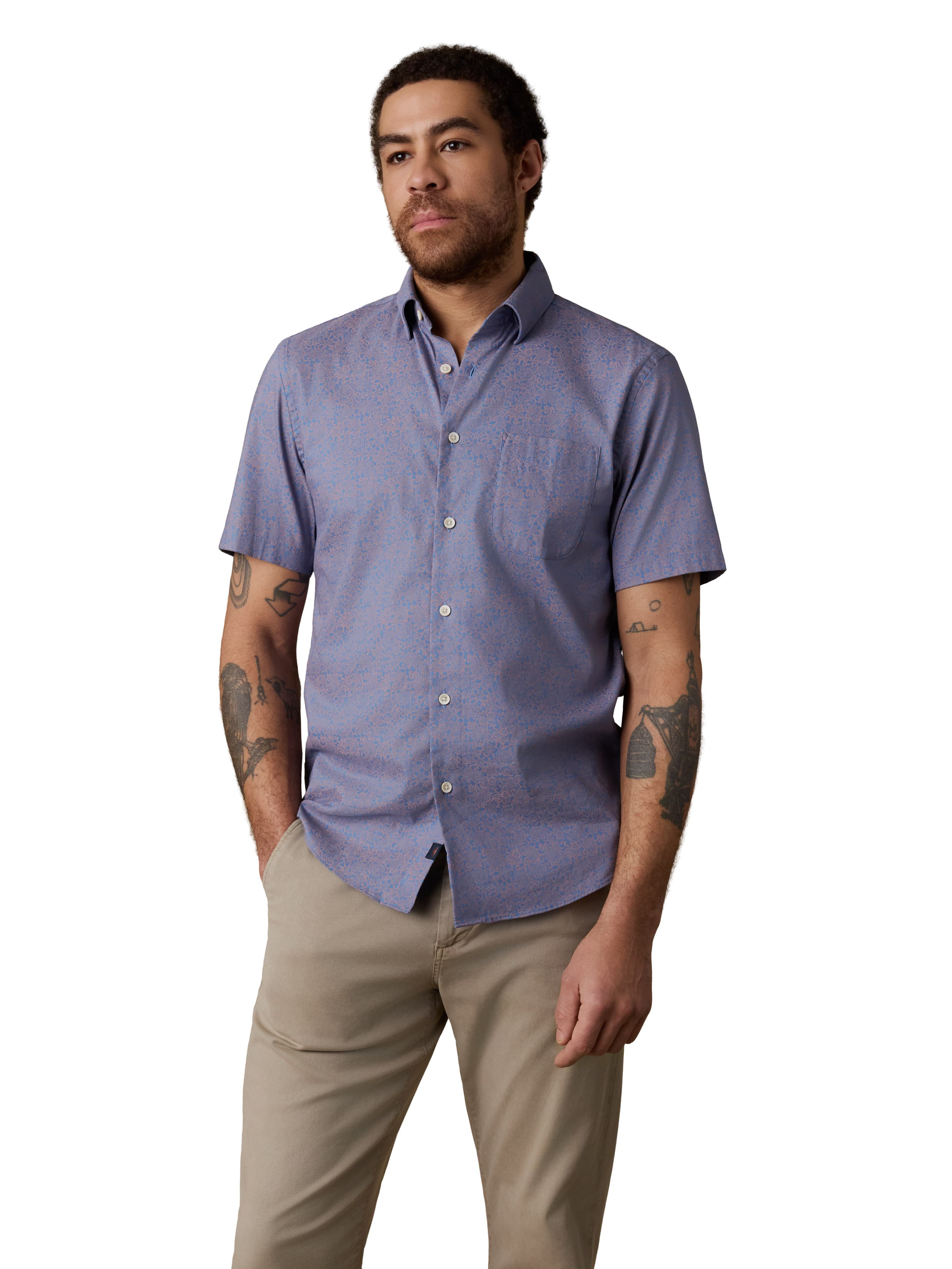 A man wearing a blue button up shirt and beige pants