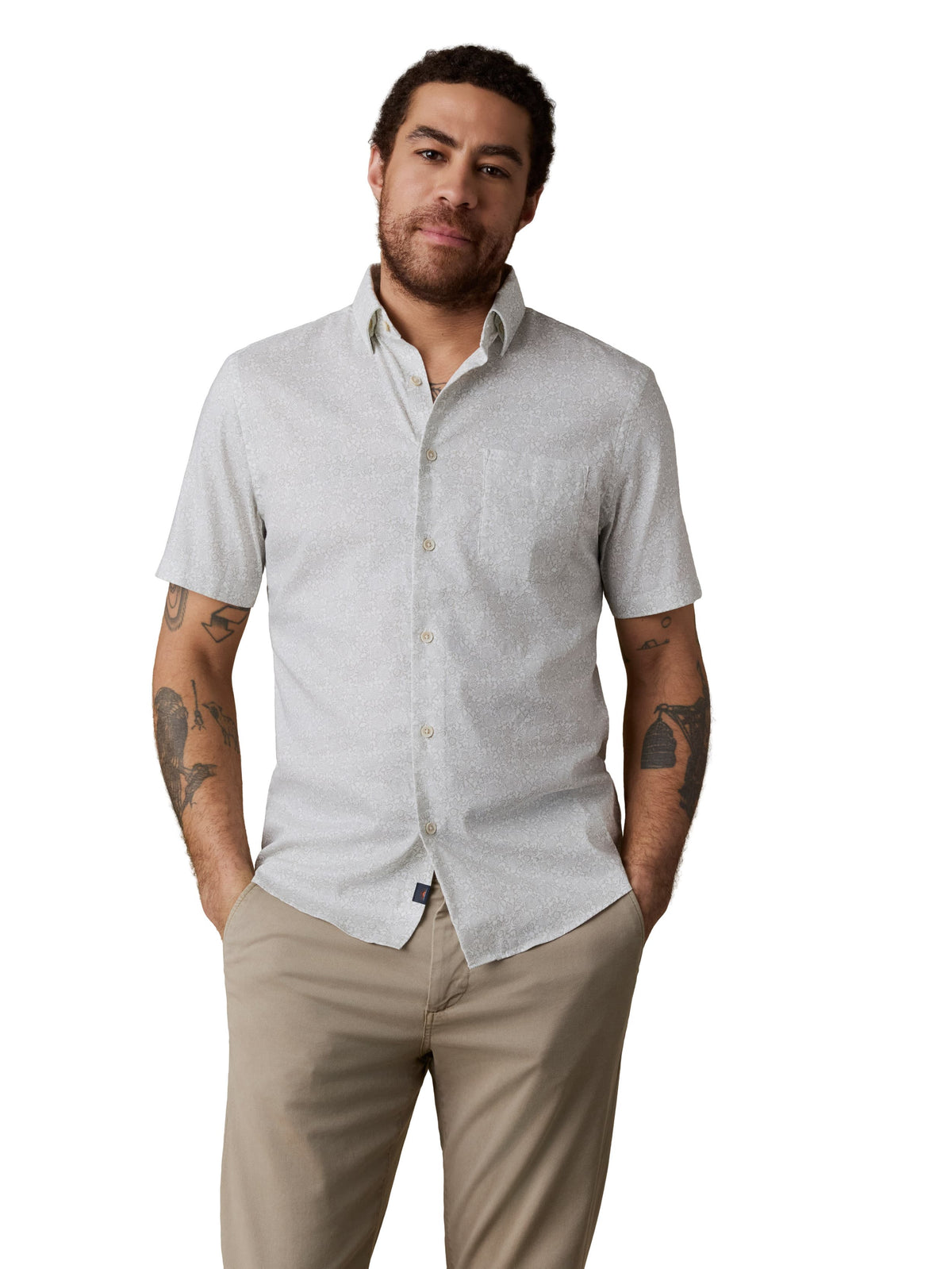 A man wearing a white button up shirt and beige pants, image 1 of 3