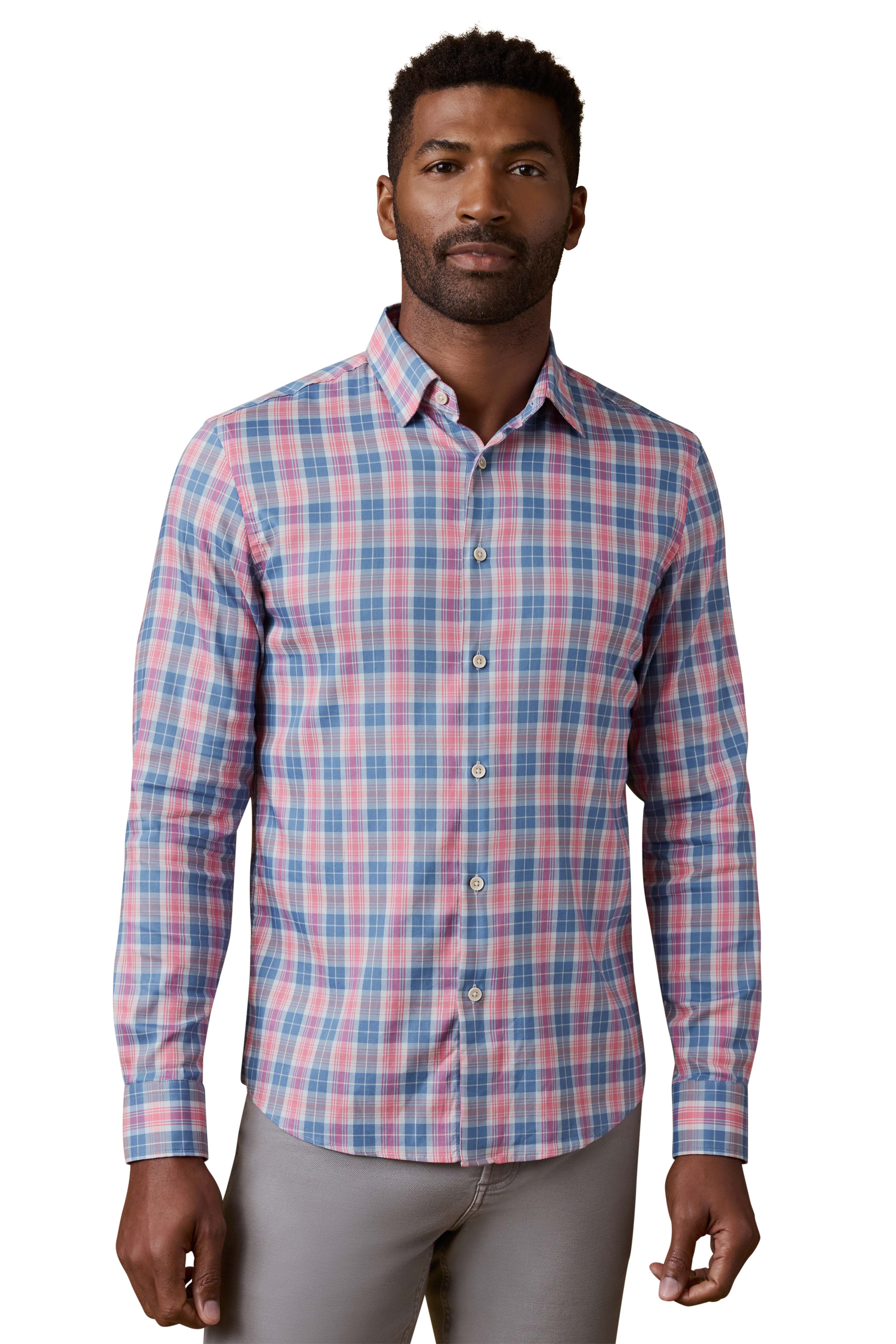 A man wearing a red and blue plaid shirt and grey pants
