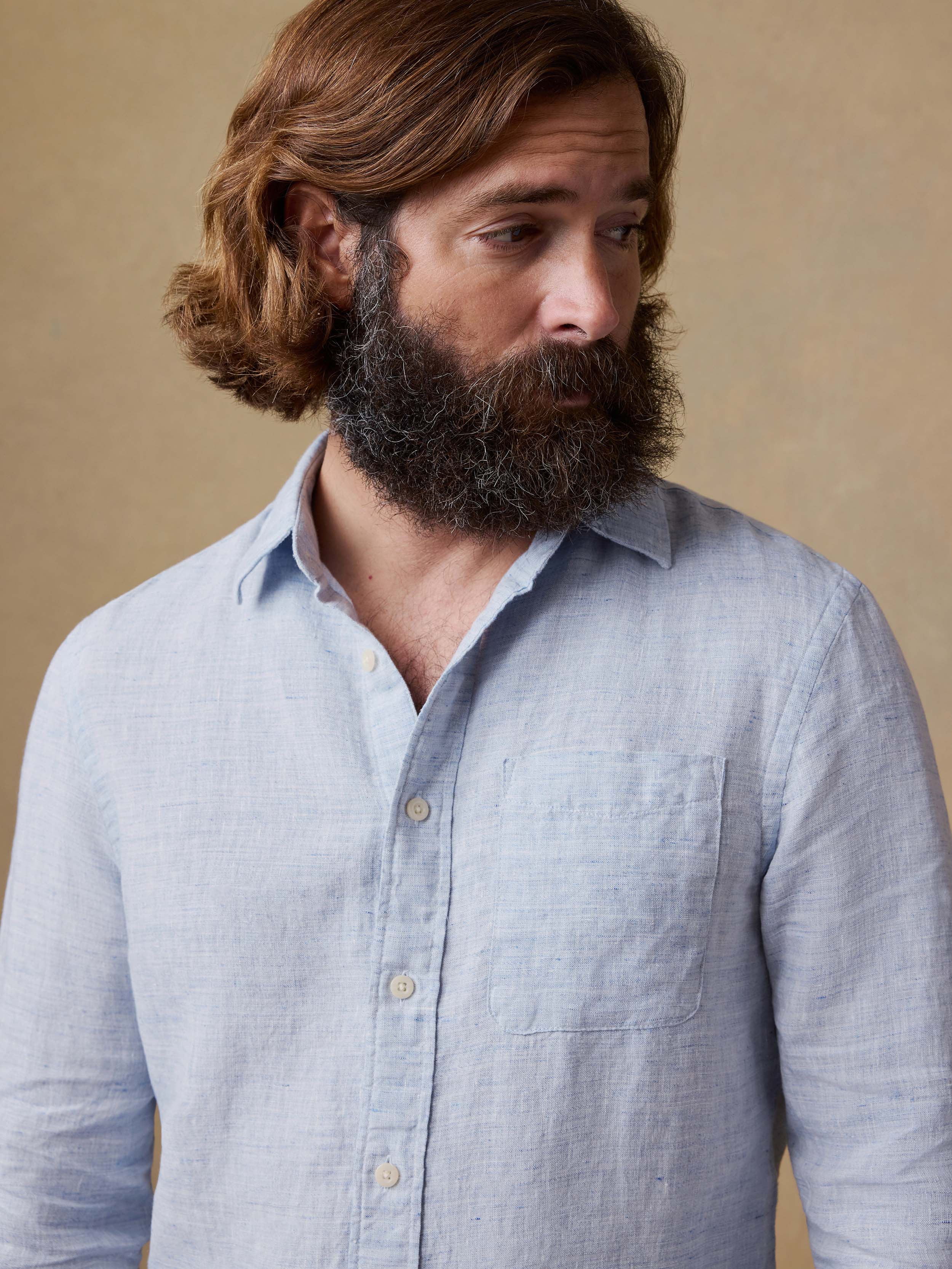 Man wearing a light blue shirt with a beige background