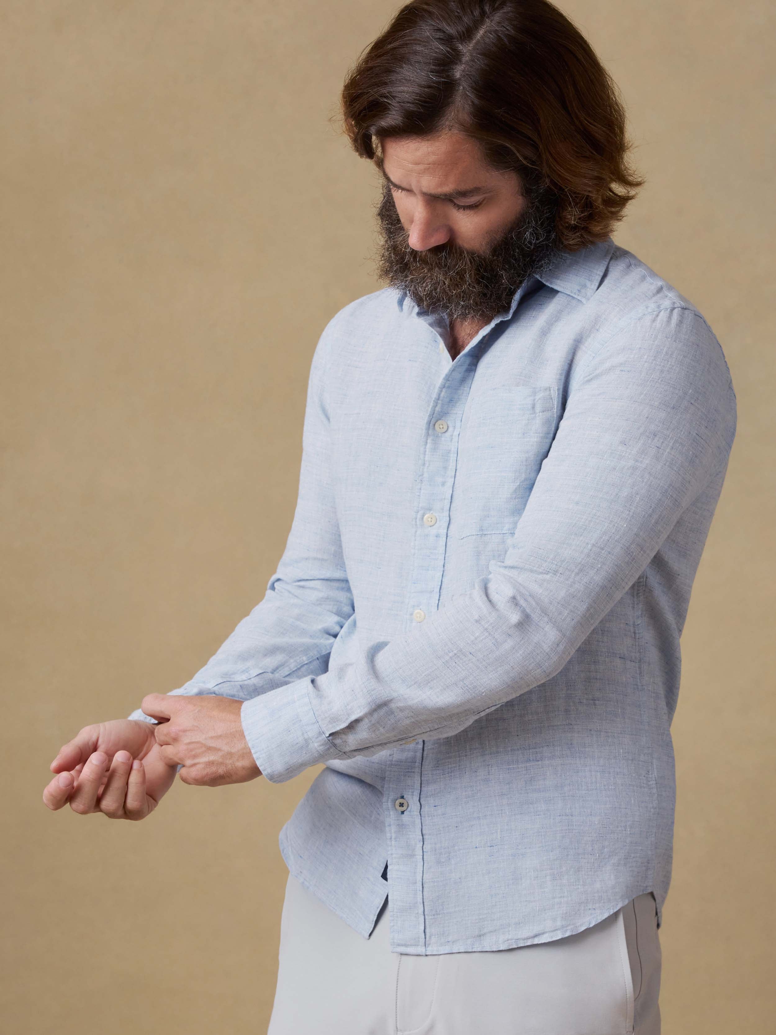 Man wearing a light blue shirt against a beige background