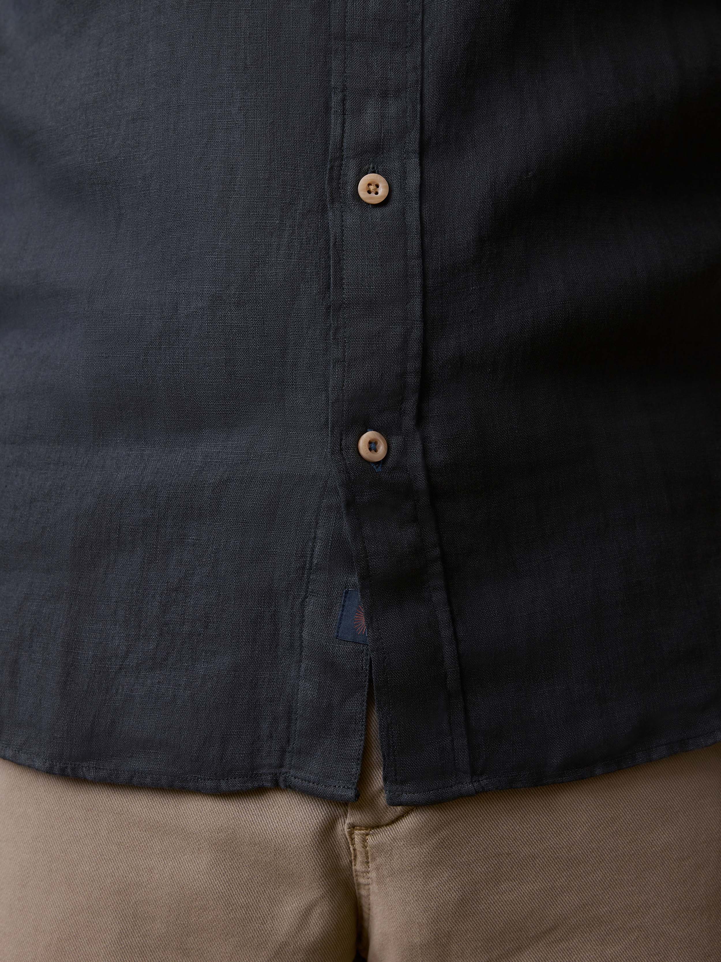 Detail shot of a man wearing a black button up shirt and beige pants