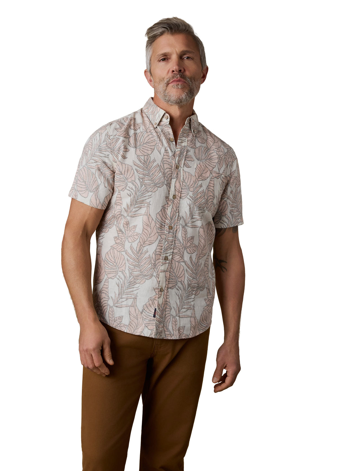 A man wearing a printed shirt and brown pants, image 1 of 3