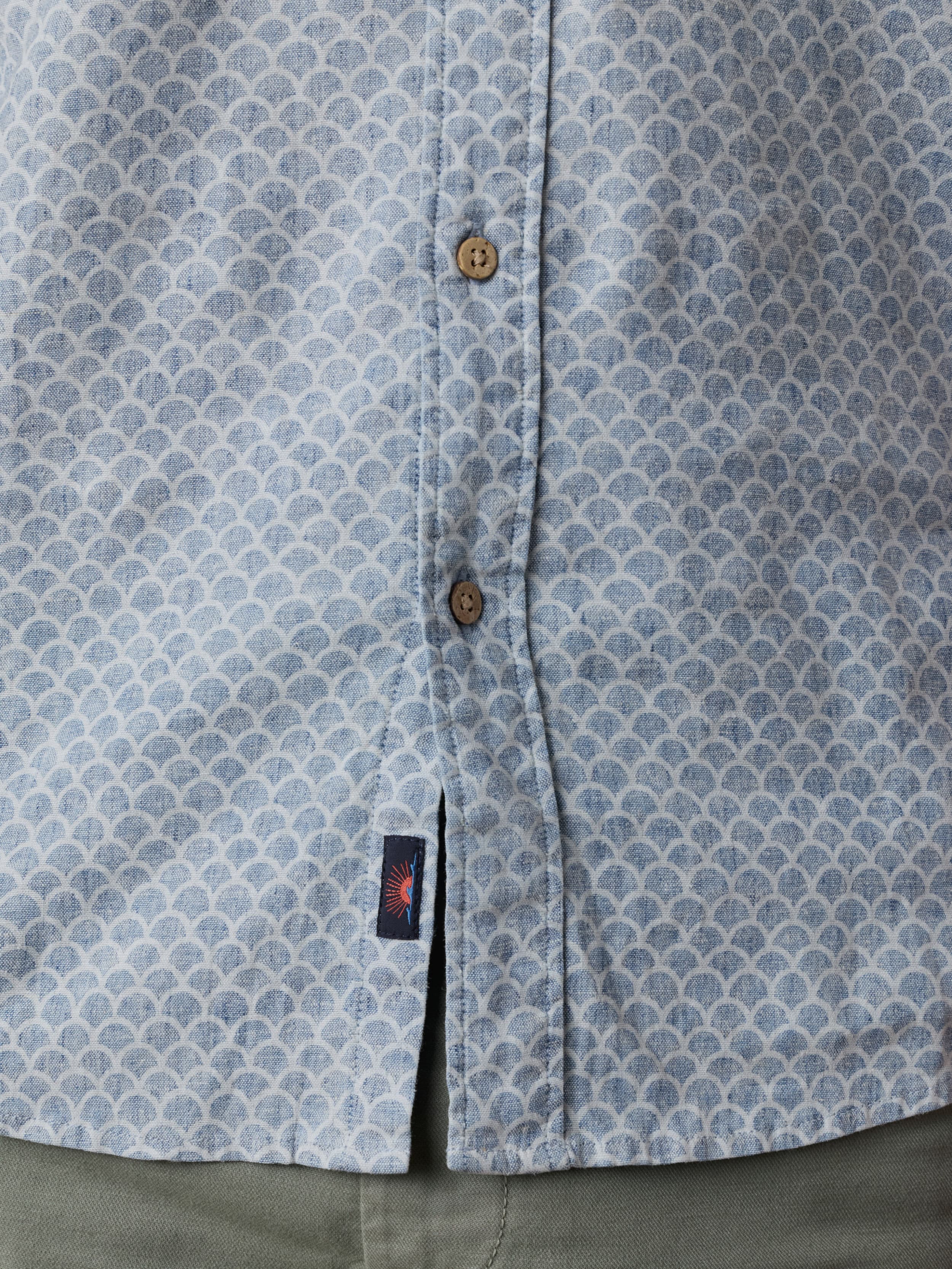 Close-up of a blue patterned shirt with visible Faherty brand logo near the hem and button details