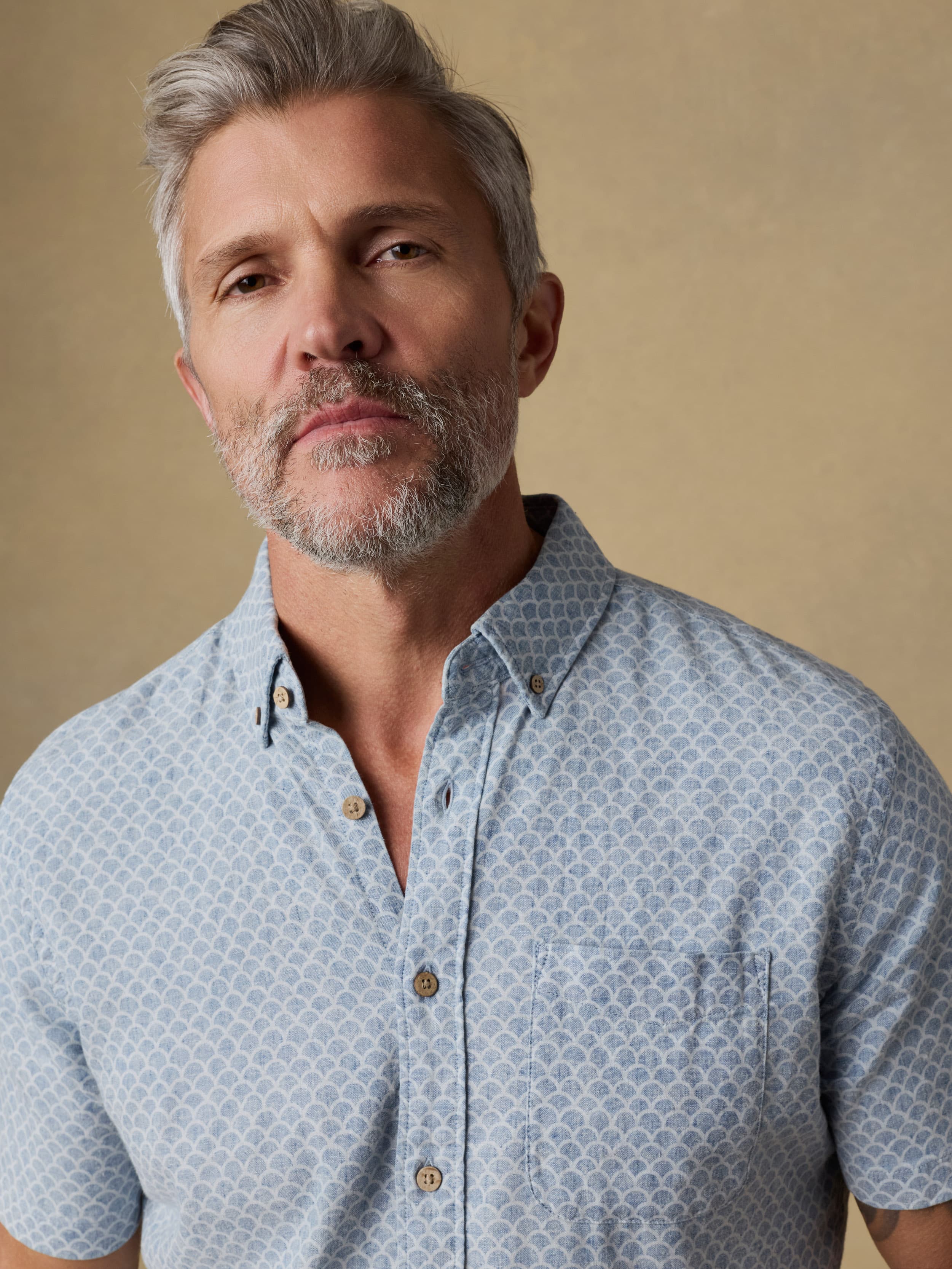Man wearing a light blue patterned shirt against a beige background