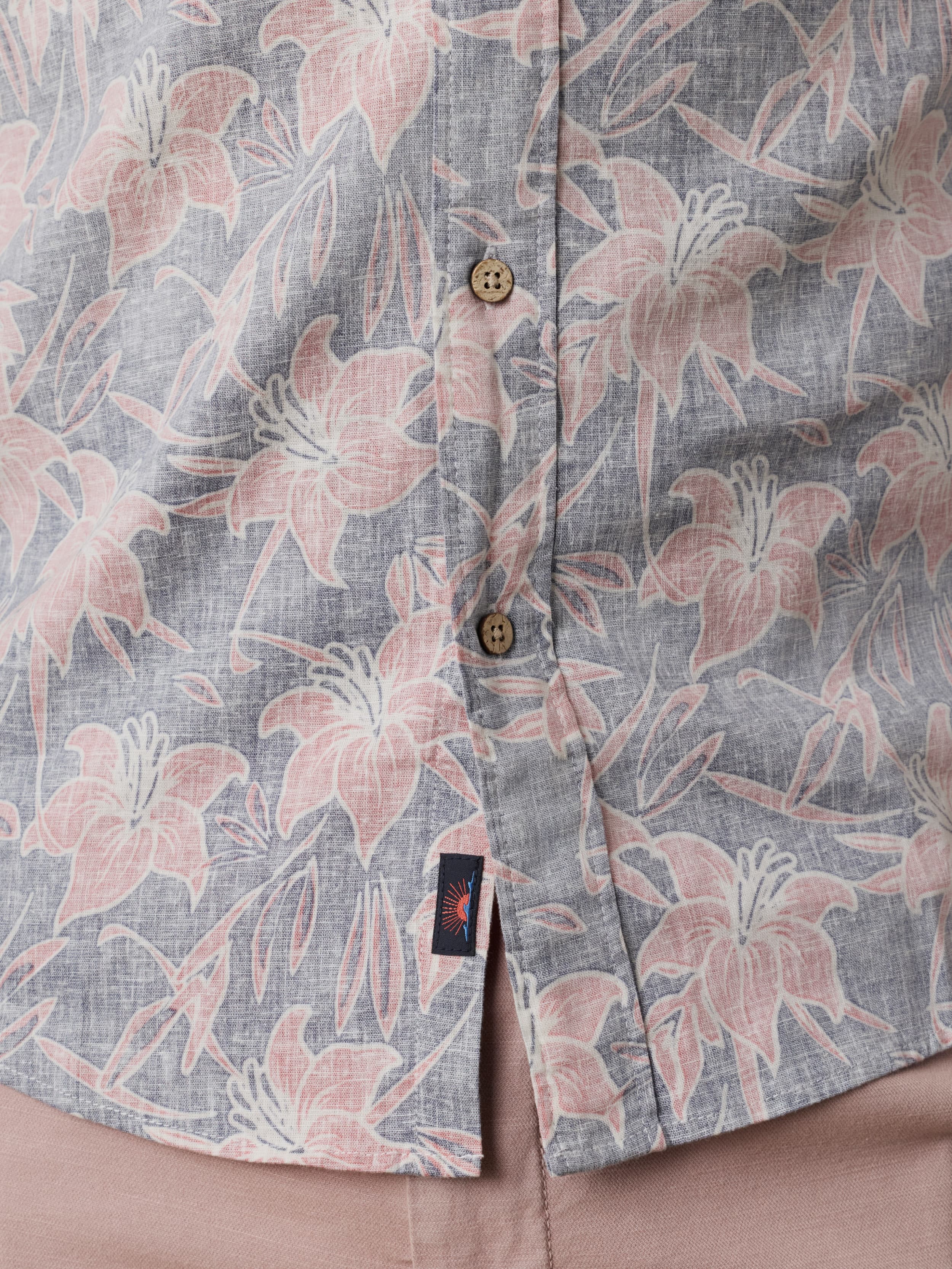 Close up shot of a floral patterned shirt with pink flowers and a visible Faherty brand logo near the hem