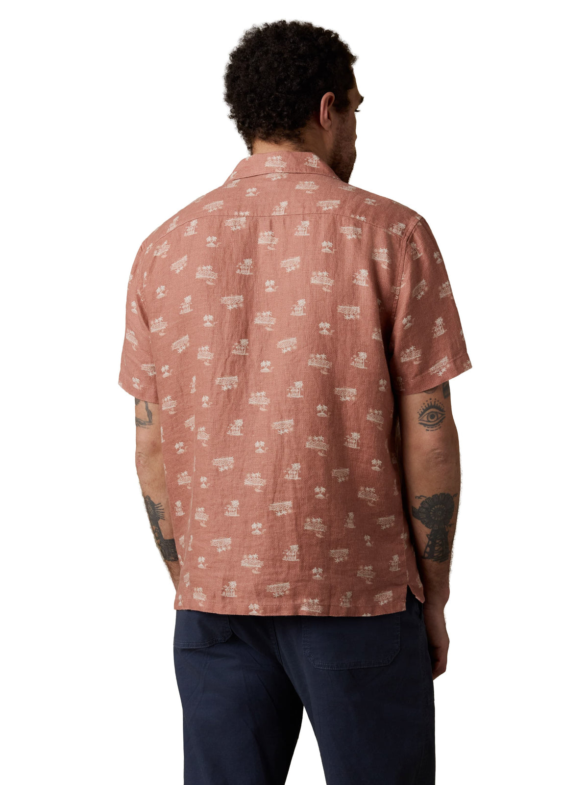A man viewed from behind wearing a red button up shirt and blue pants, image 3 of 3