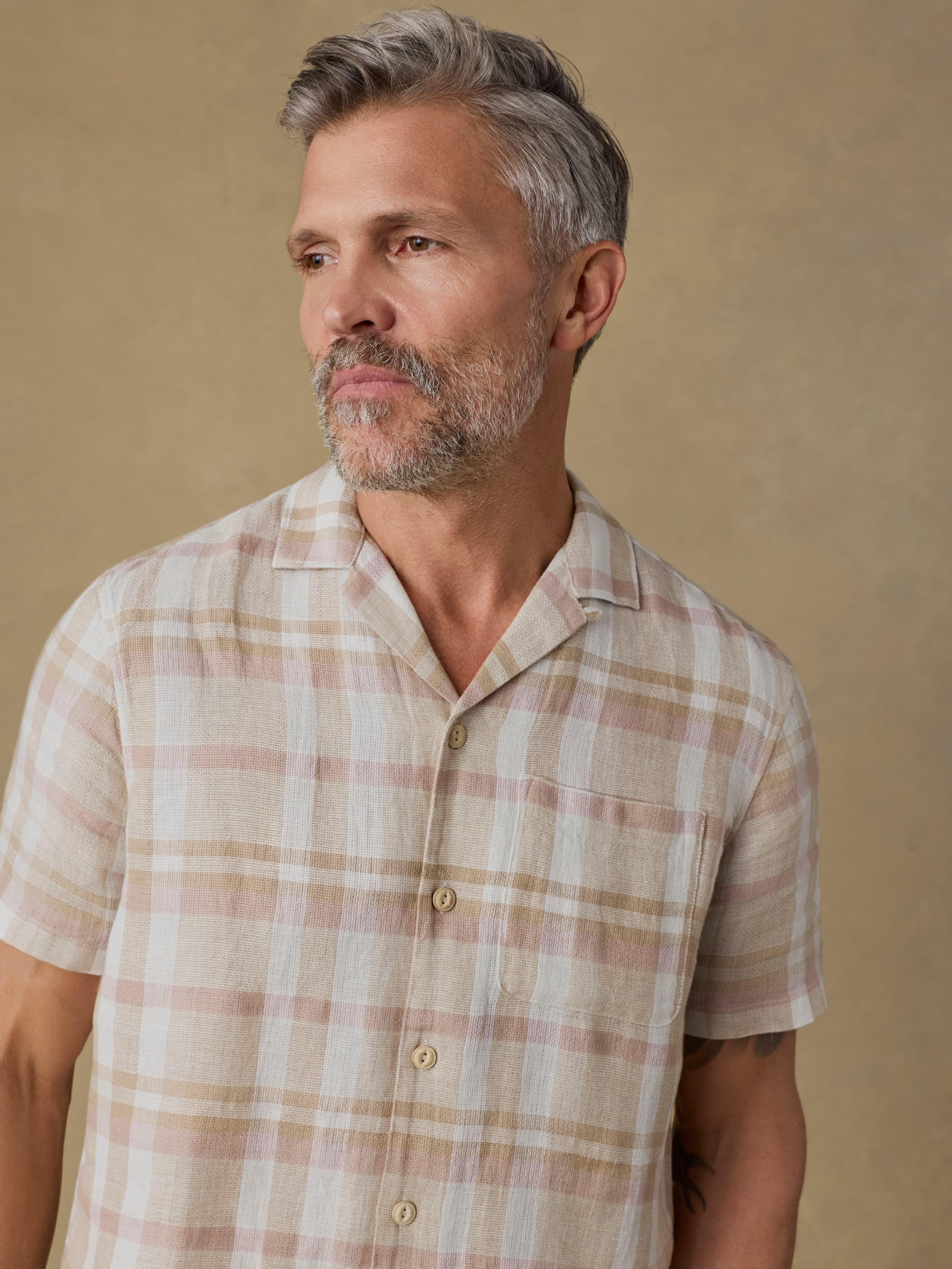 Man wearing a plaid shirt against a beige background