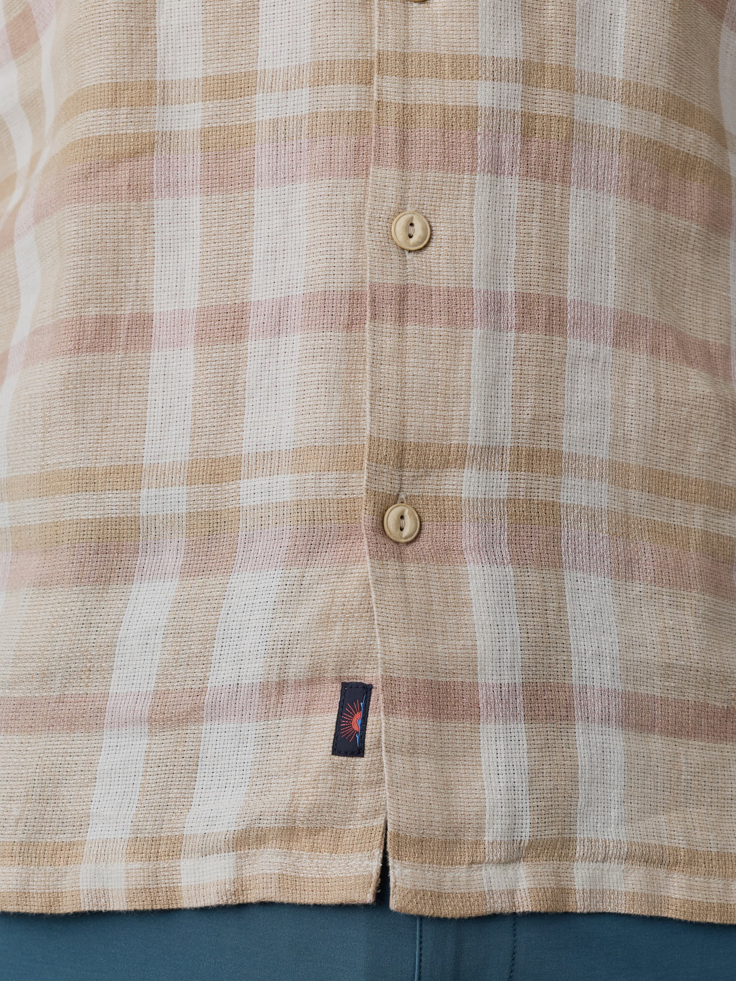 Close-up of a plaid shirt with a Faherty brand logo near the hem