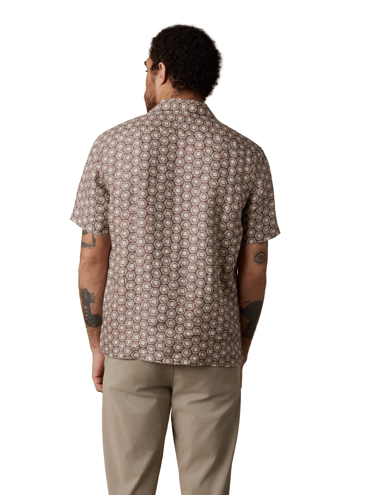 A man viewed from behind wearing a brown printed shirt and beige pants, image 3 of 3