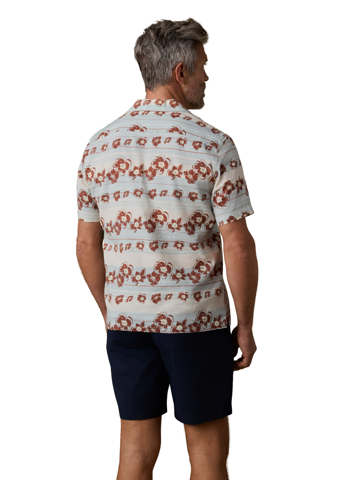 A man viewed from behind wearing a floral printed button up shirt and black shorts, image 3 of 3