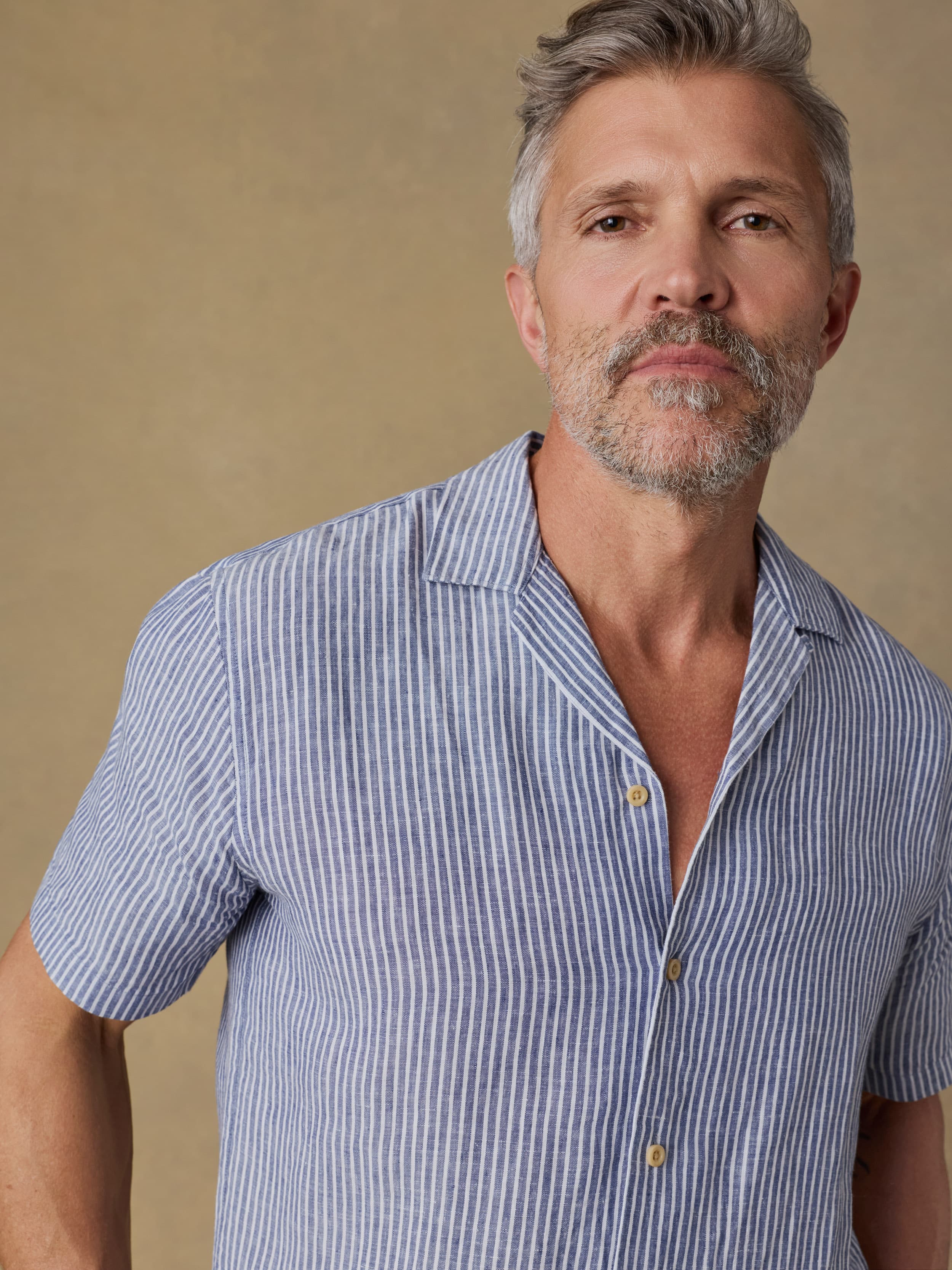 Man wearing a blue striped shirt against a brown background