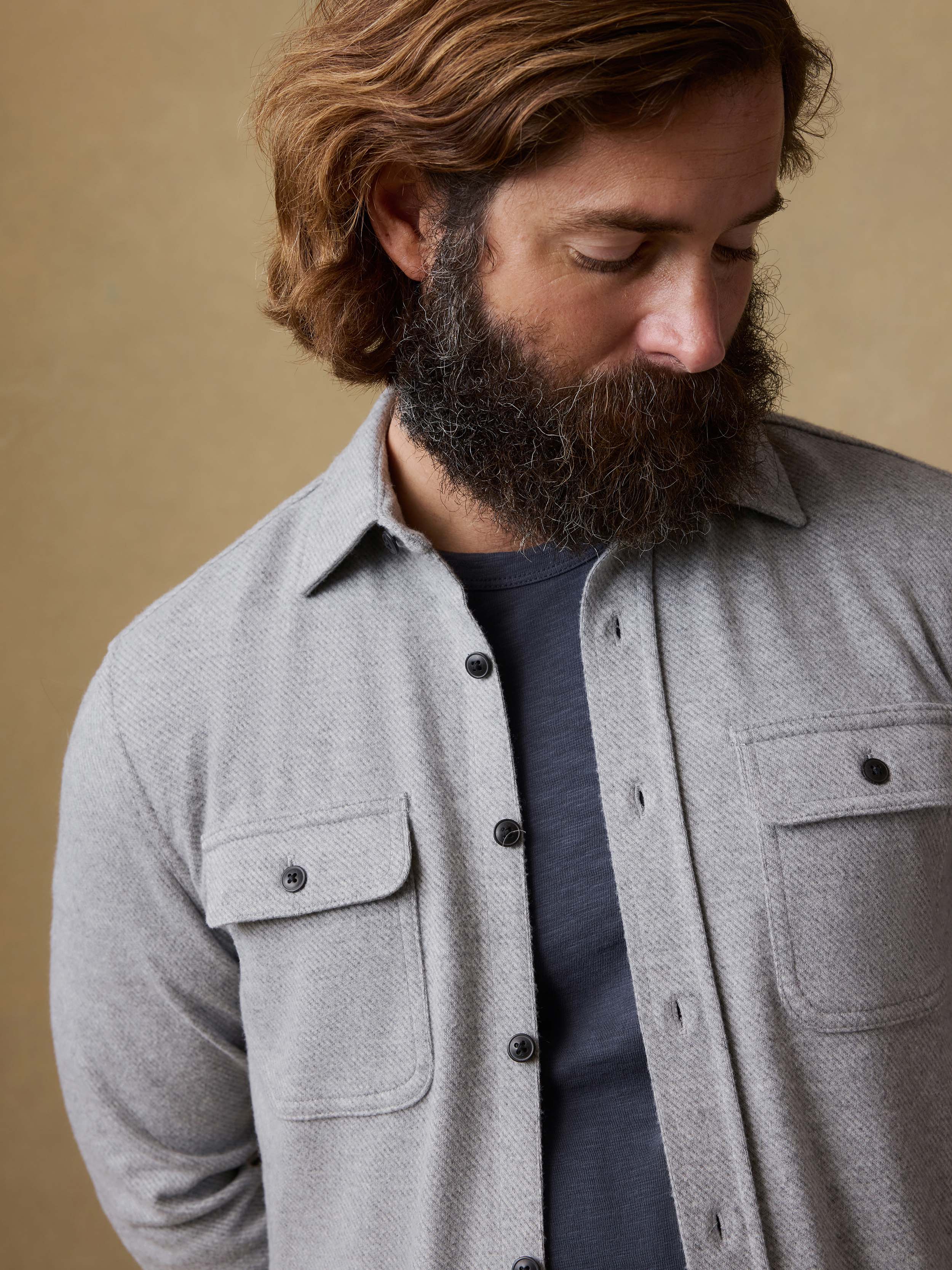 Man wearing a gray long-sleeve shirt against a beige background