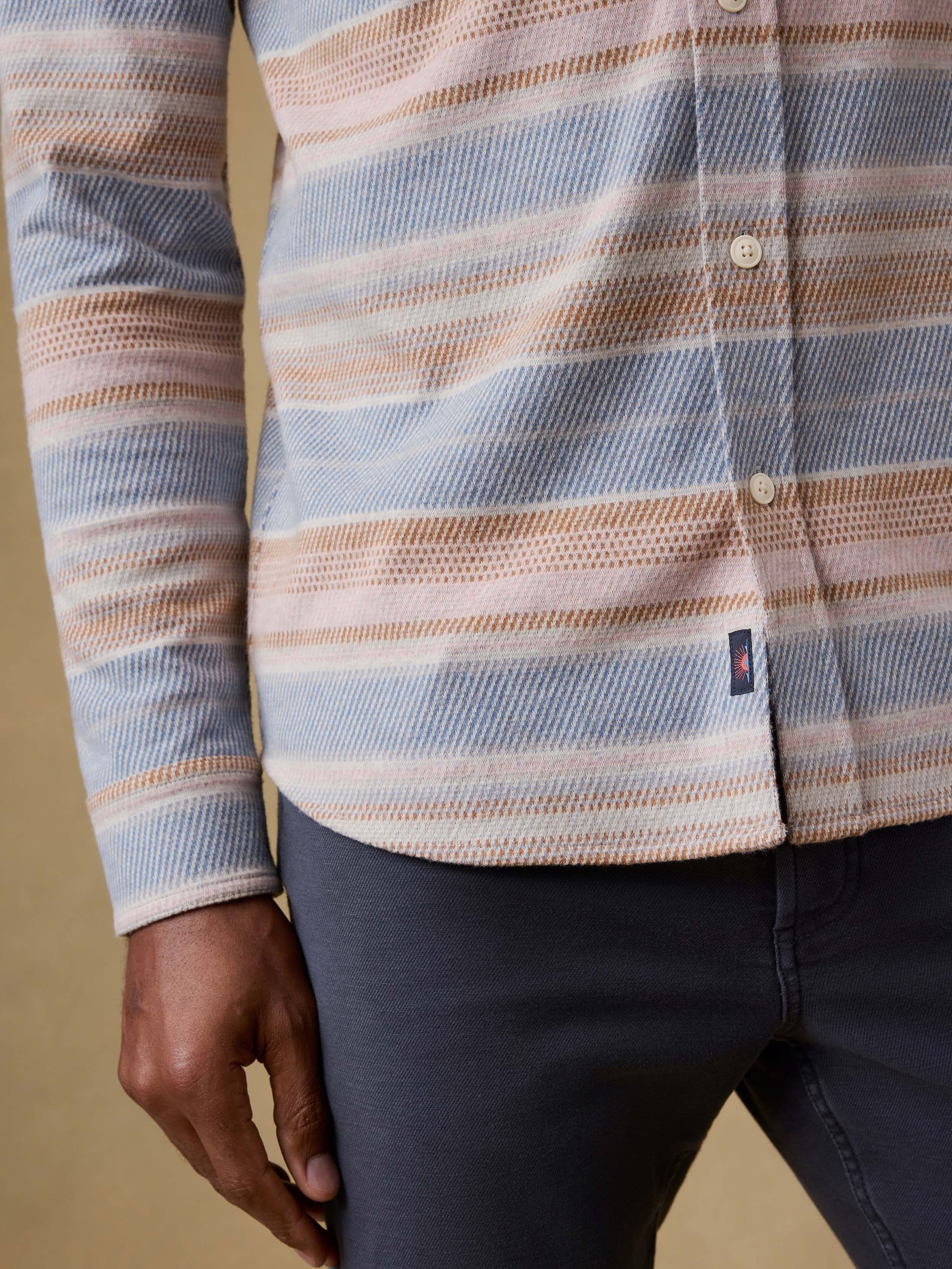 Close-up of a man wearing a plaid shirt with a visible Faherty brand logo on a beige background