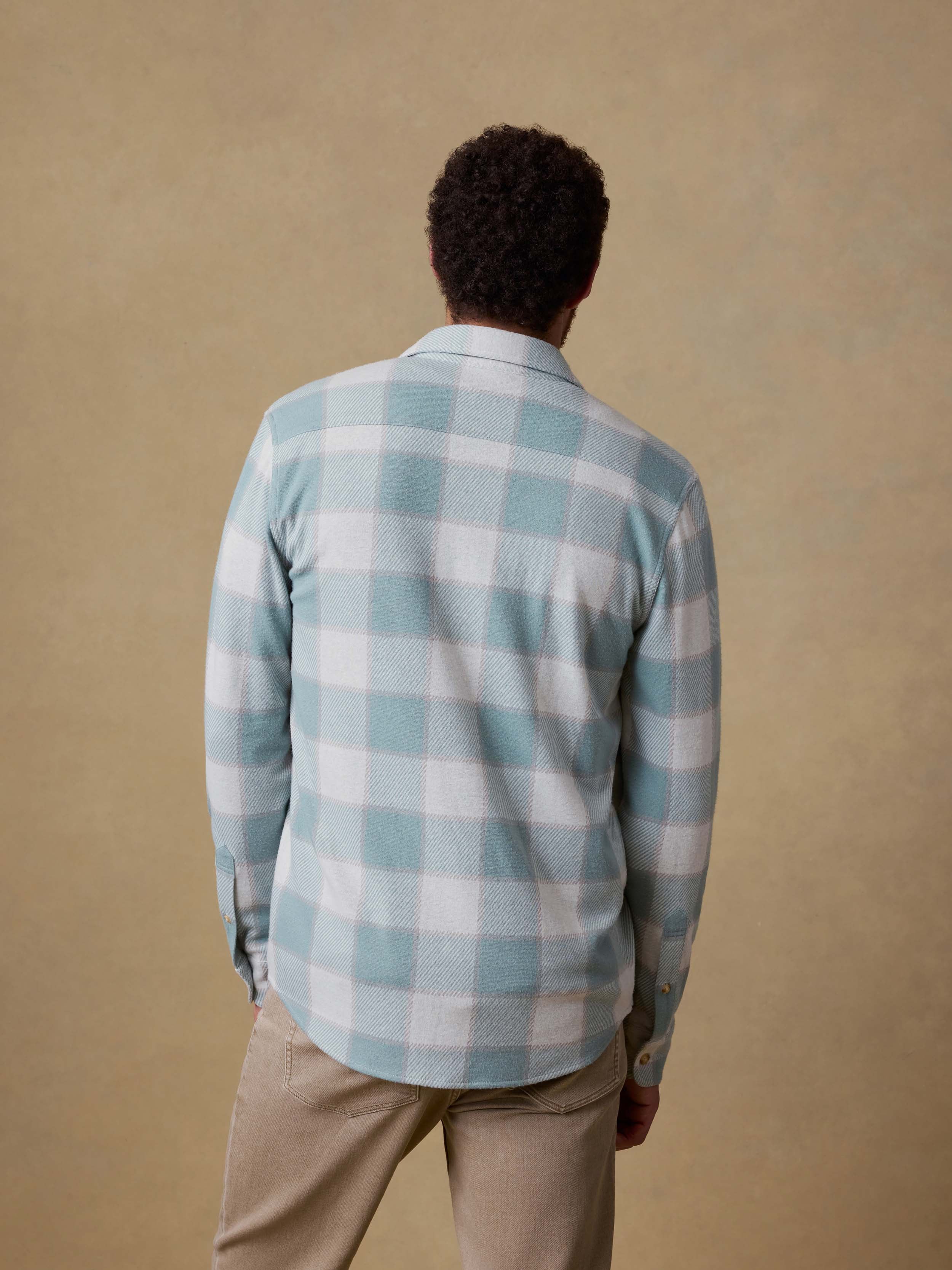 Man wearing a blue and white checkered shirt against a beige background