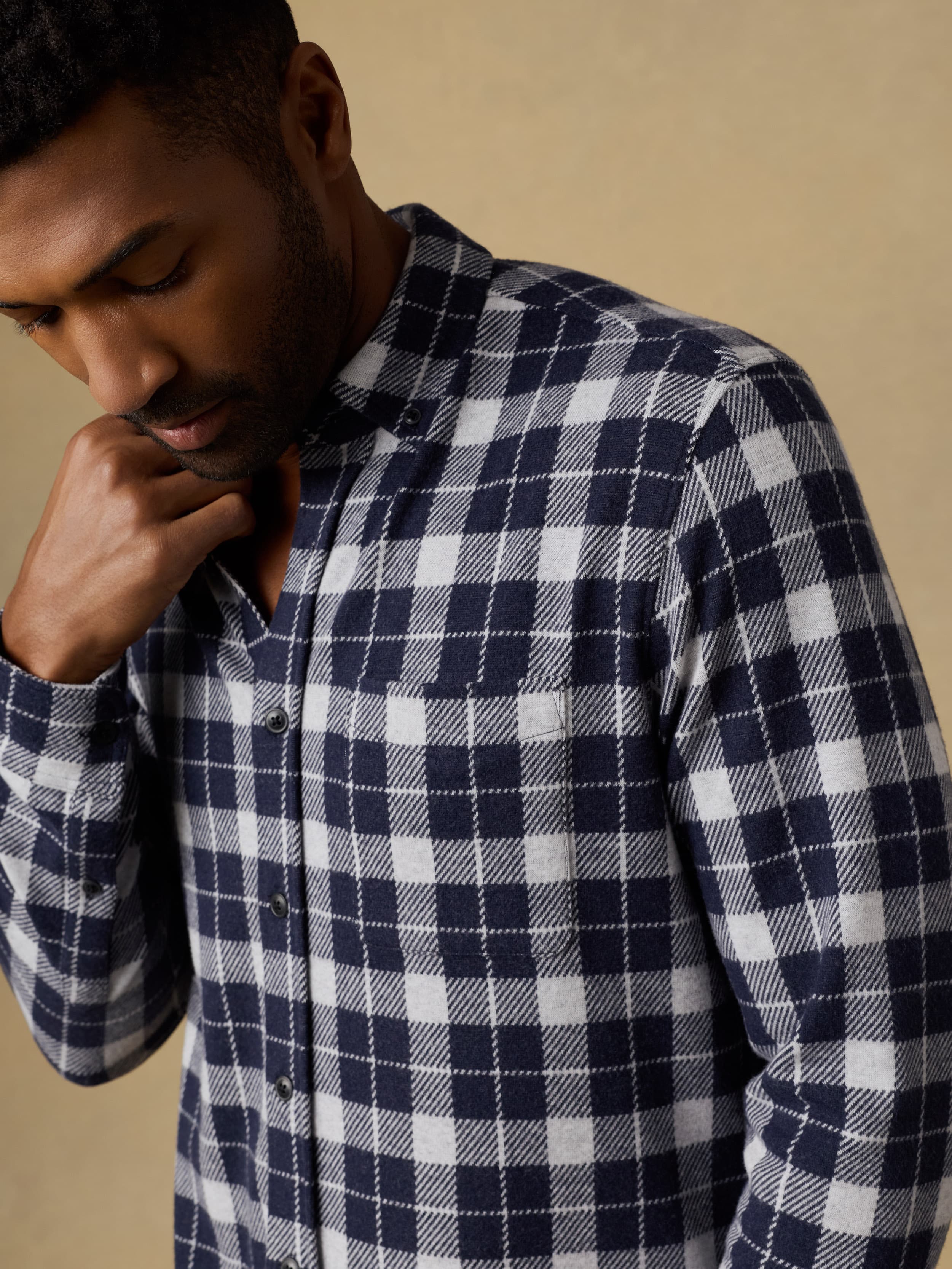 Man wearing a blue and white checkered shirt against a beige background