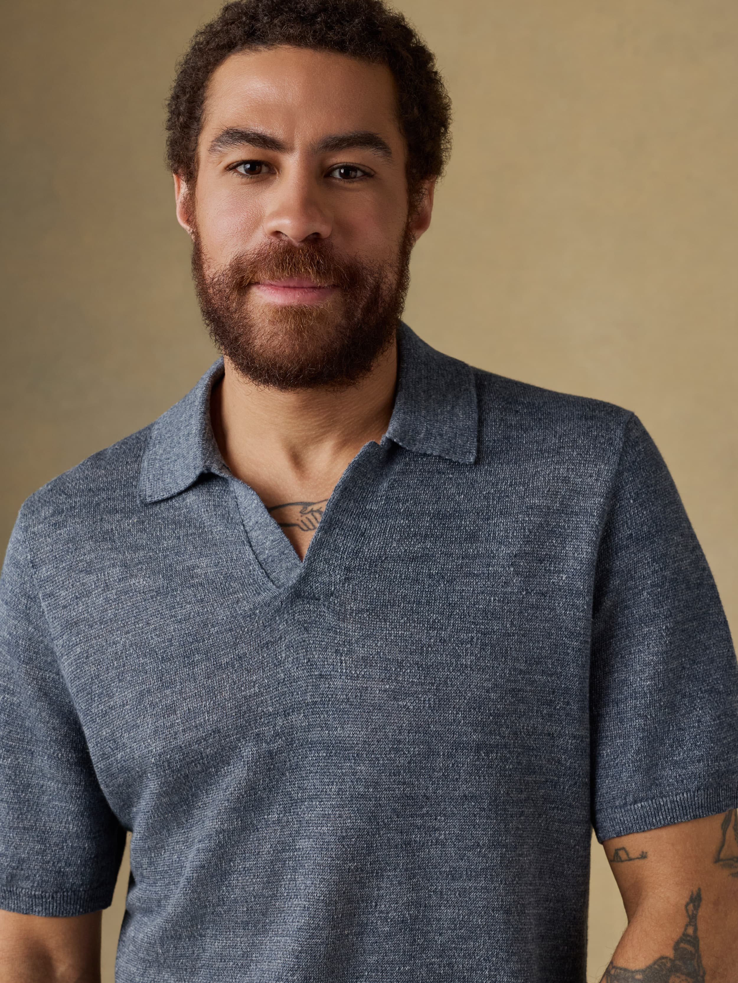 Man wearing a blue polo shirt against a beige background