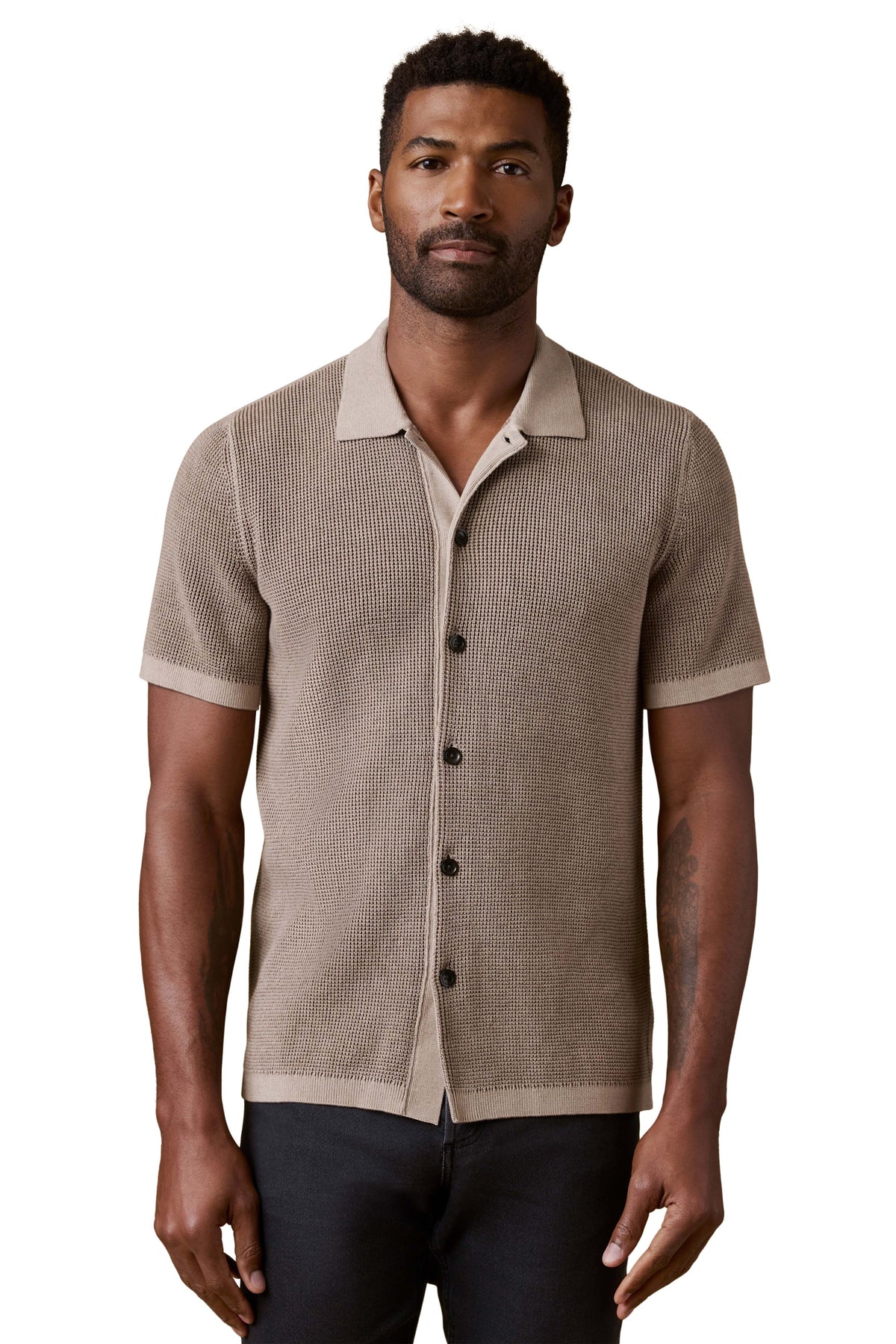 A man wearing a brown polo and dark jeans, image 1 of 3