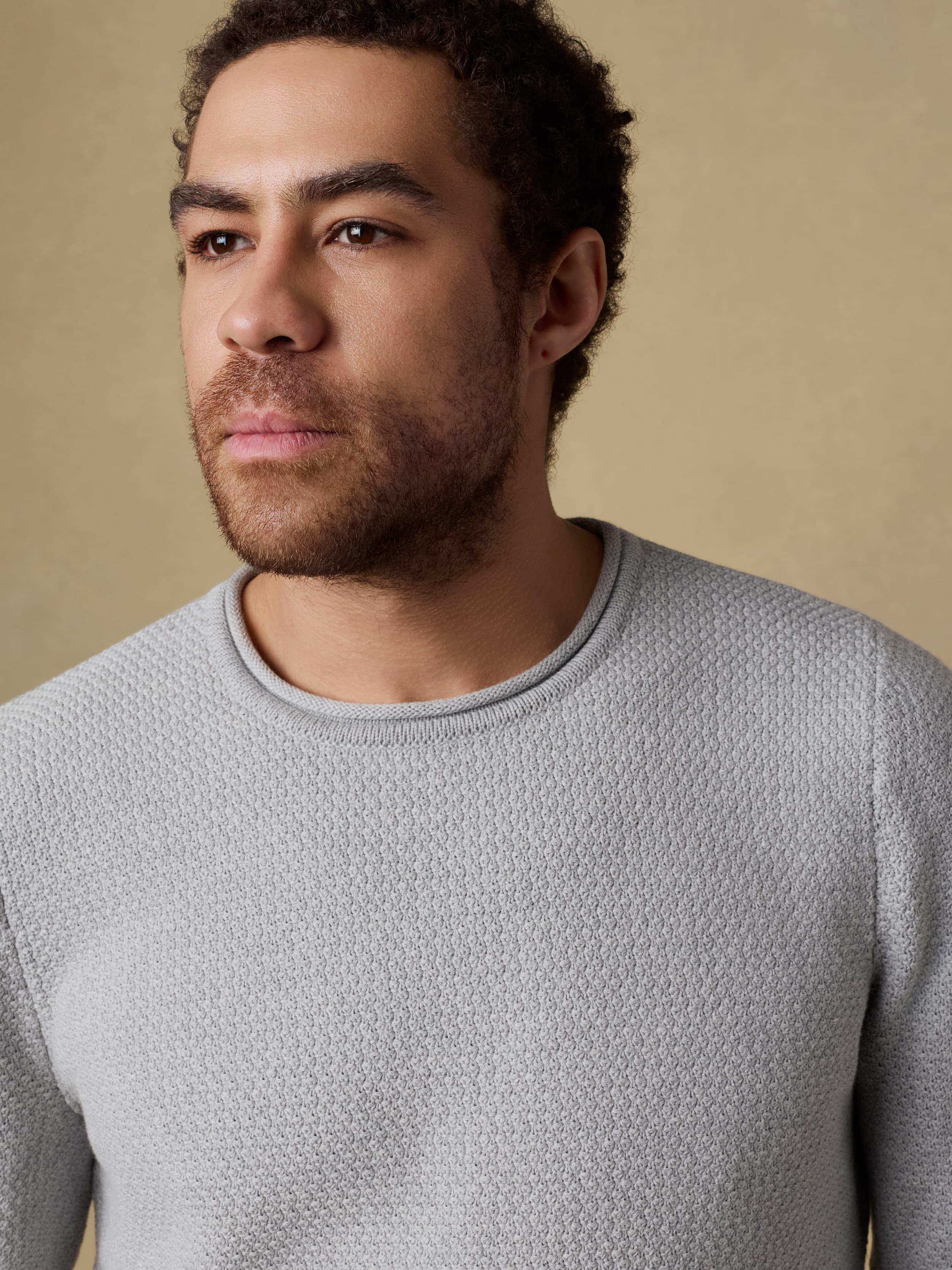 Man wearing a gray sweater against a beige background