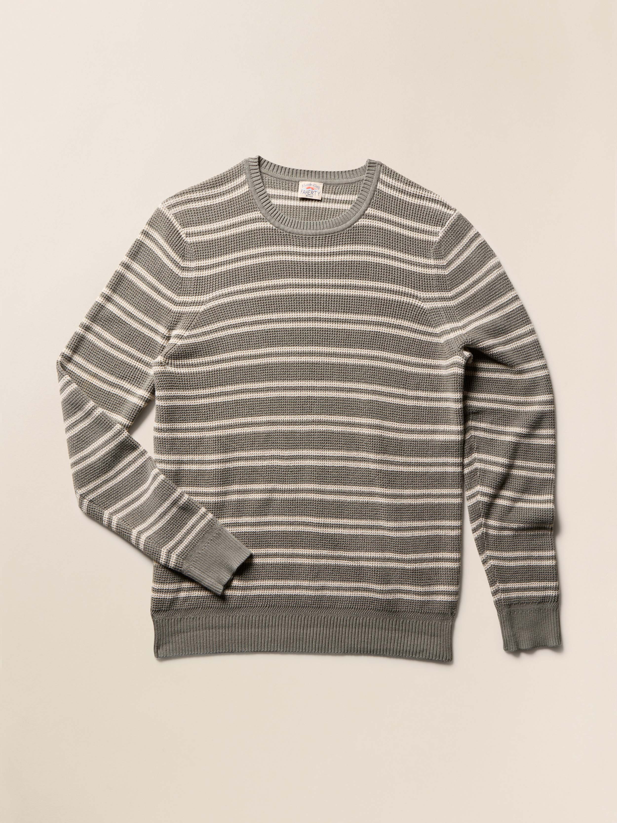 Sage green and ivory striped crewneck sweater against a beige background