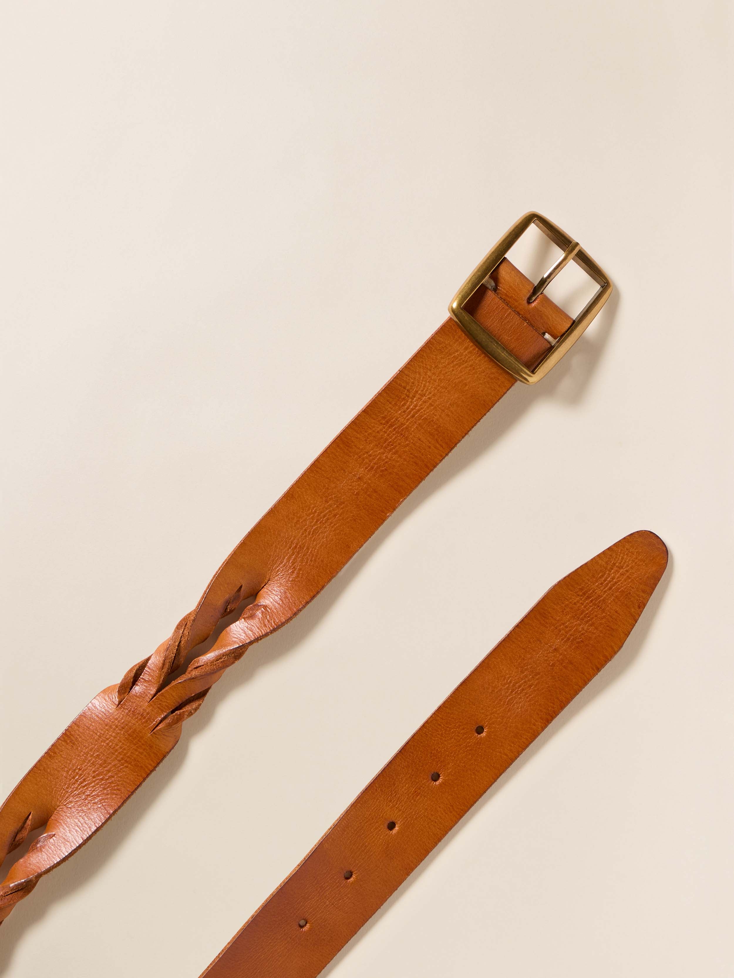 Brown leather belt with a gold buckle on a beige background