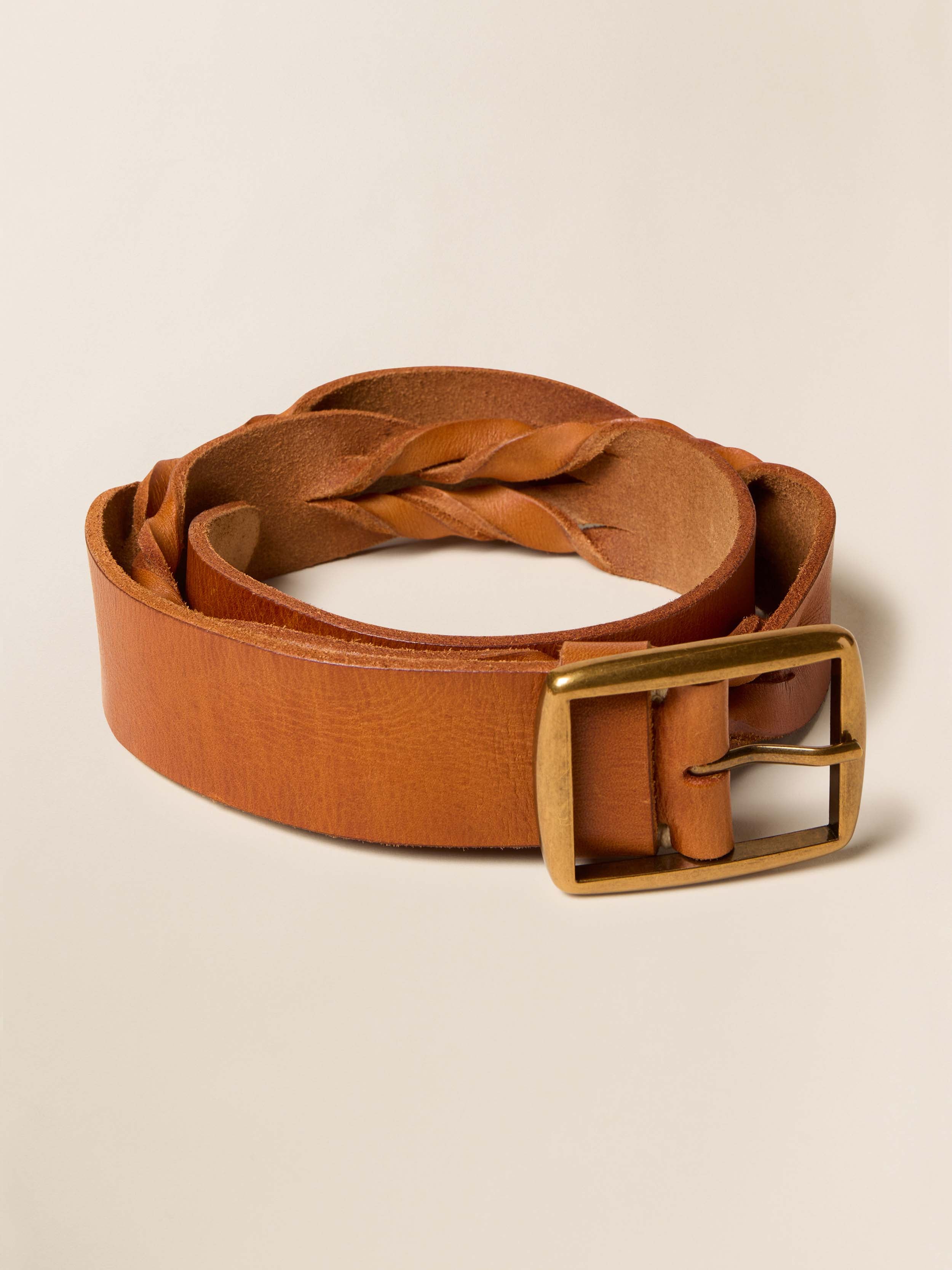 Brown leather belt with a gold buckle on a beige background