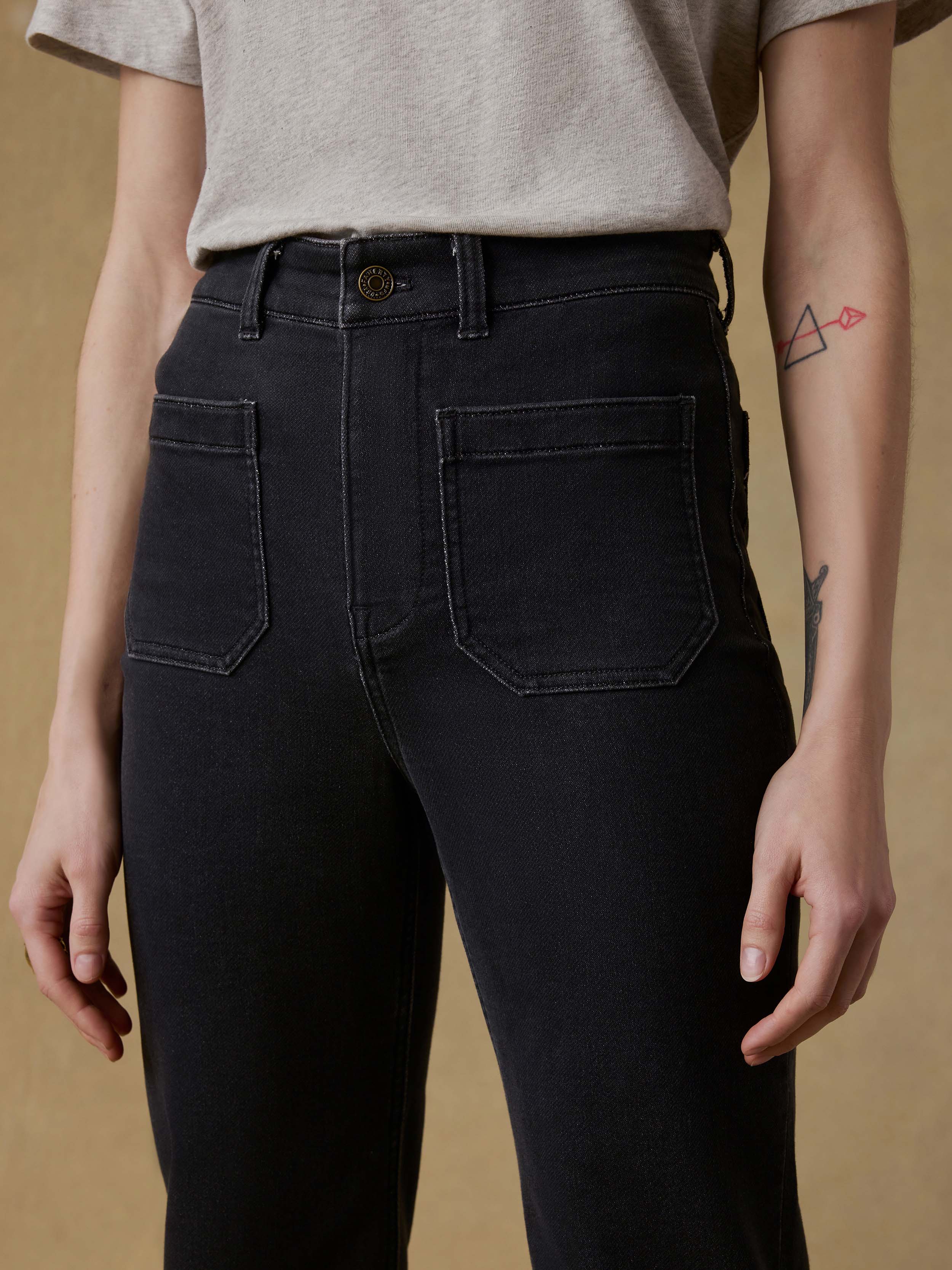 Woman wearing a light gray t-shirt and black pants against a beige background