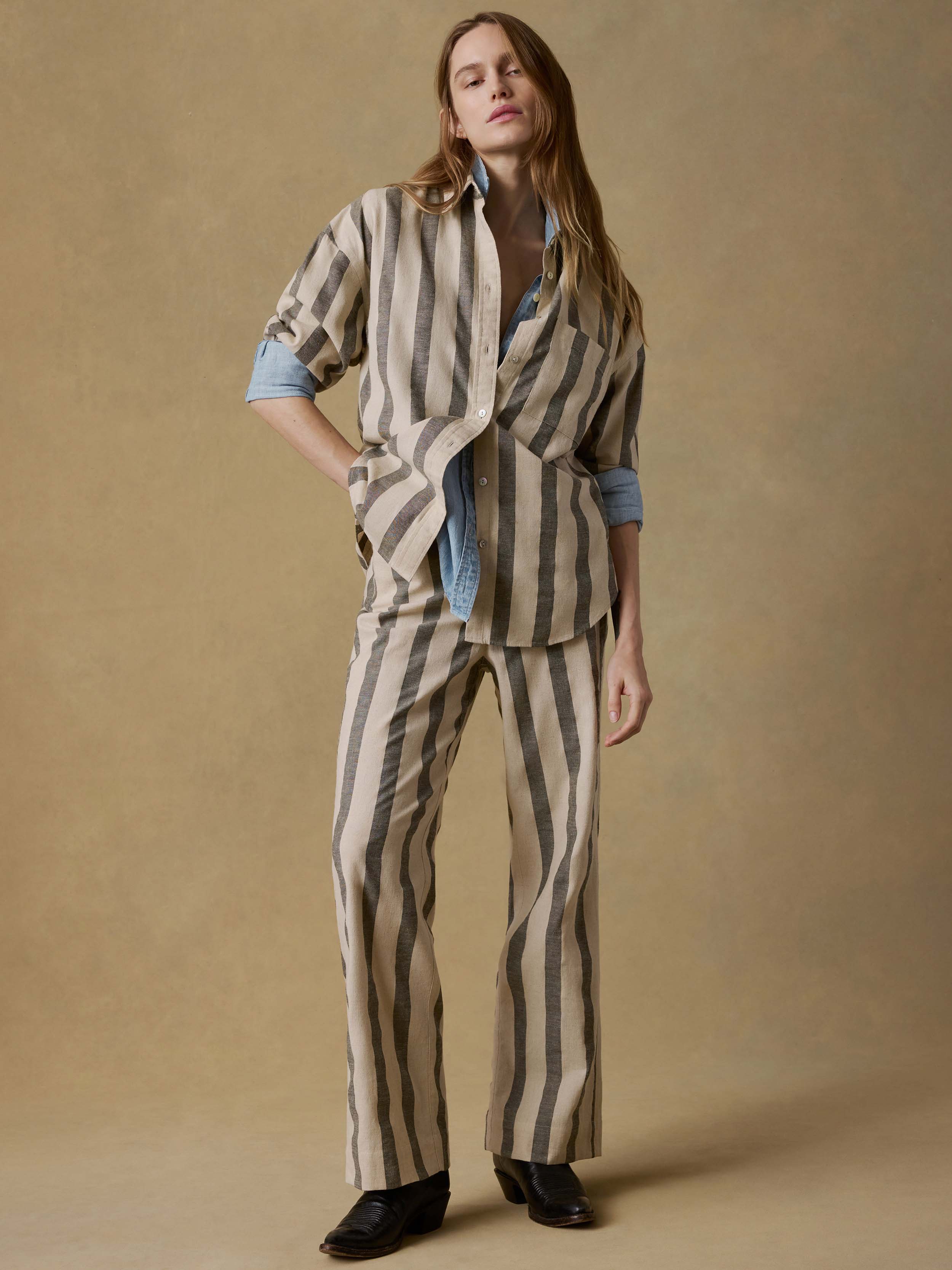 Woman wearing a matching green striped top and pant against a beige background